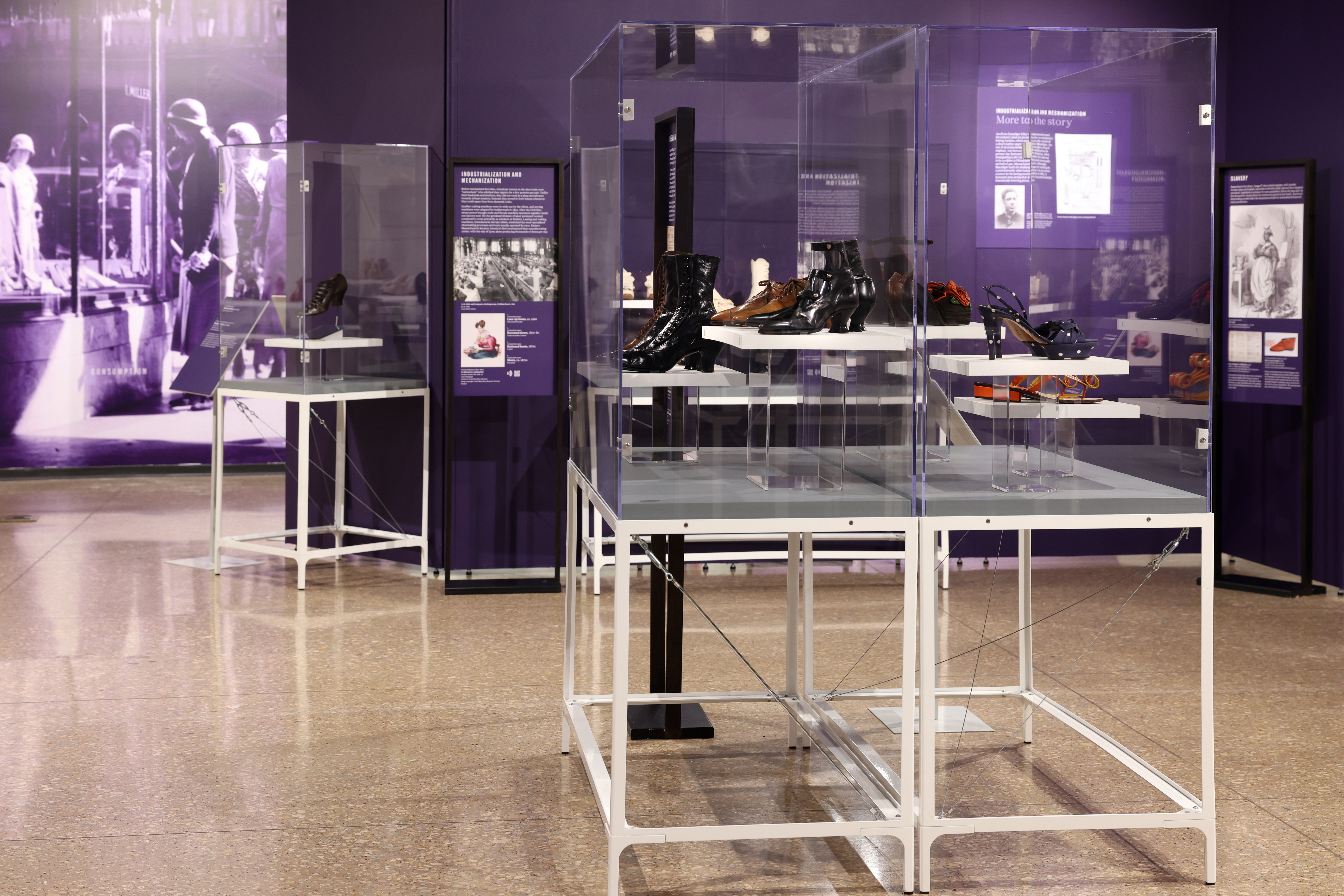 Glass display case inside a museum exhibition with various pairs of vintage shoes inside.