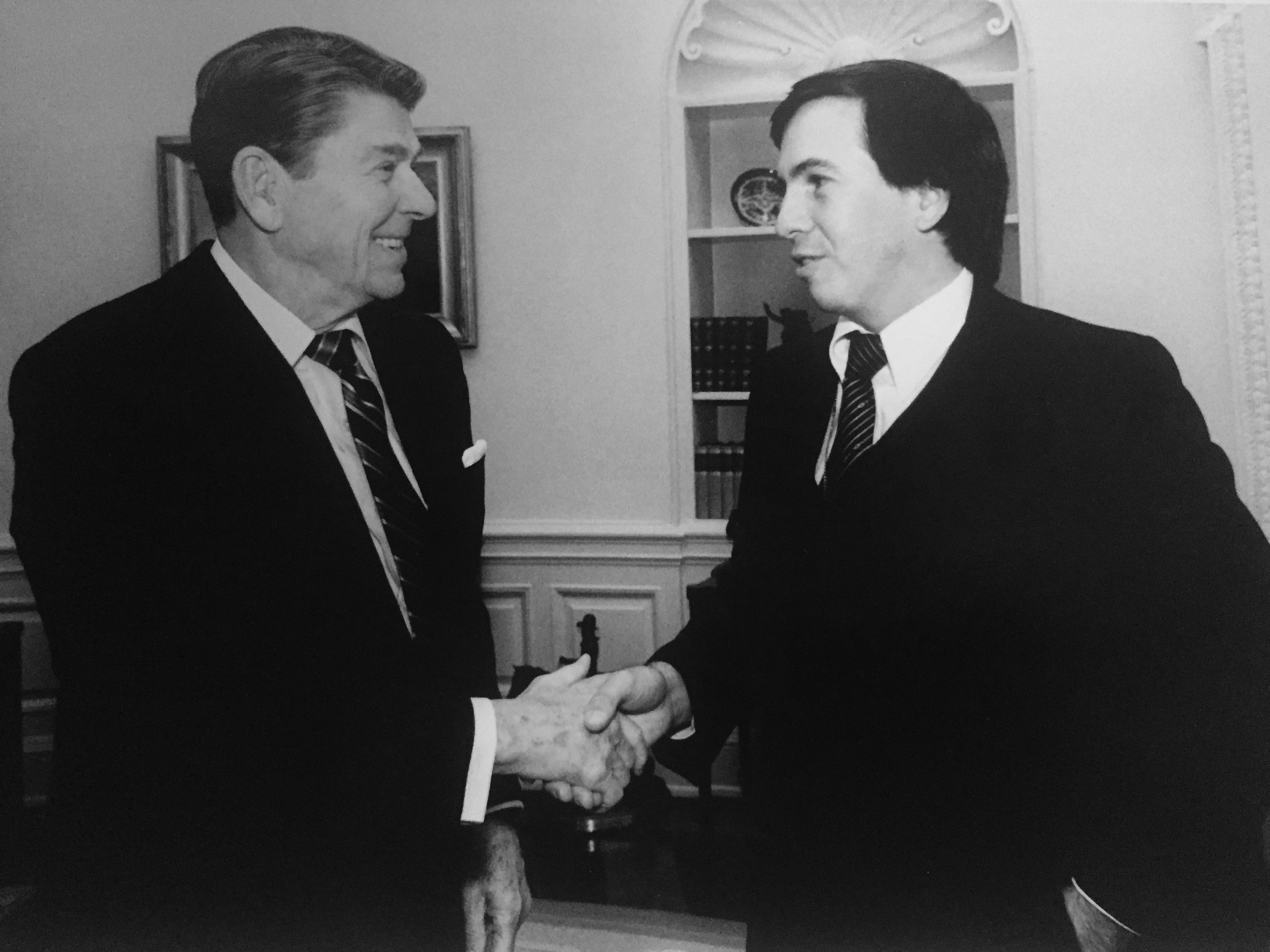 President Ronald Reagan (left) shakes hands with David Woo, who was a staff photographer for...