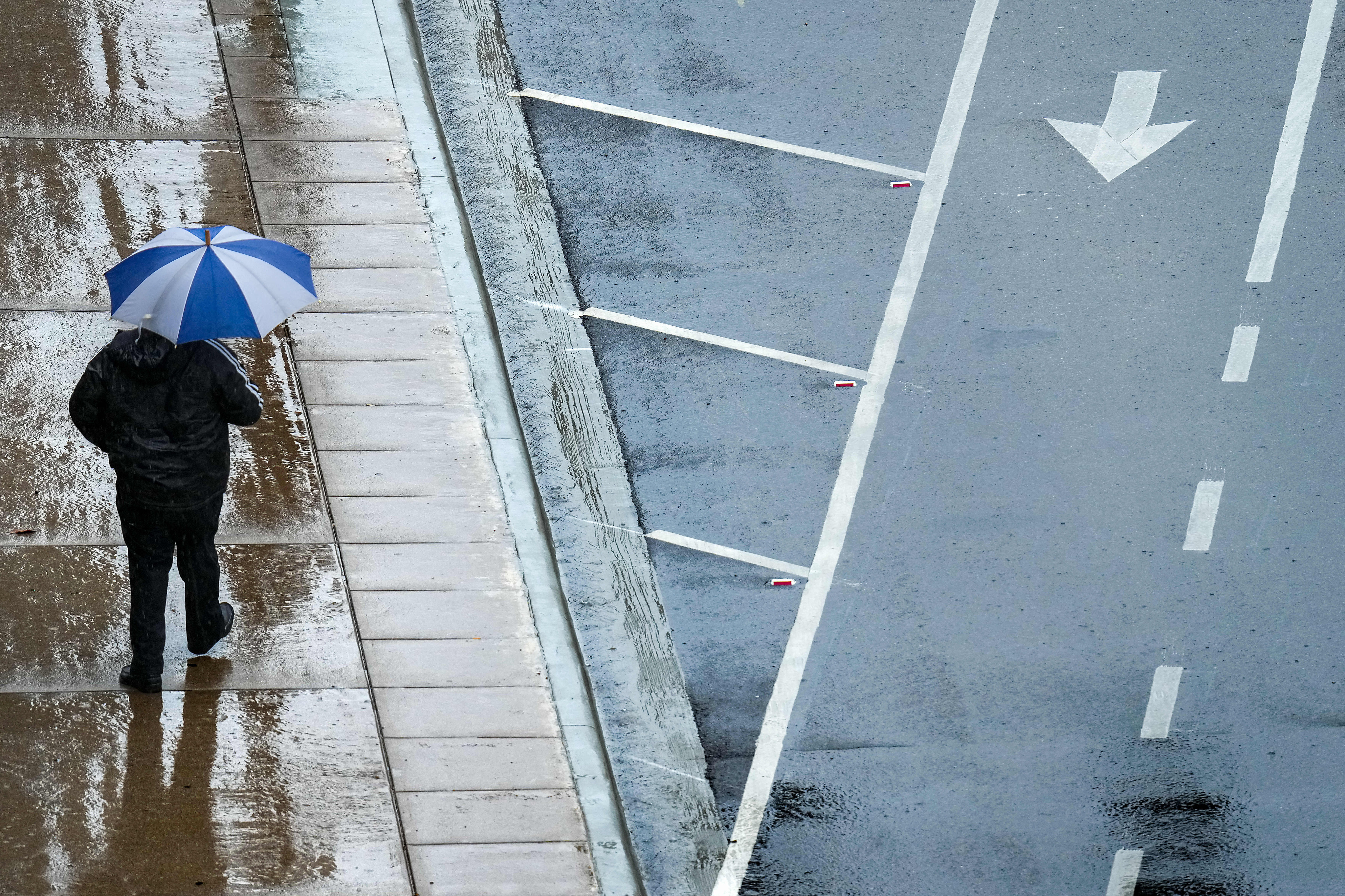 A downtown pedestrian takes cover from a cold rain along Harwood Street on Wednesday, April...