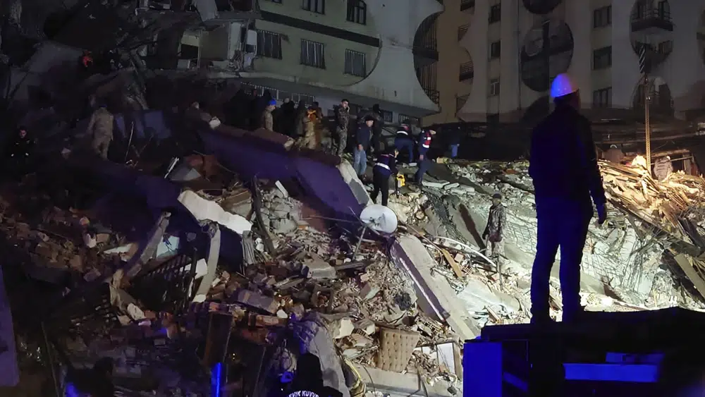 La gente intenta llegar a los residentes atrapados en un edificio derrumbado en Diyarbakir, sureste de Turquía, la madrugada del lunes 6 de febrero de 2023, tras un poderoso terremoto. (AP Photo/Mahmut Bozarsan).