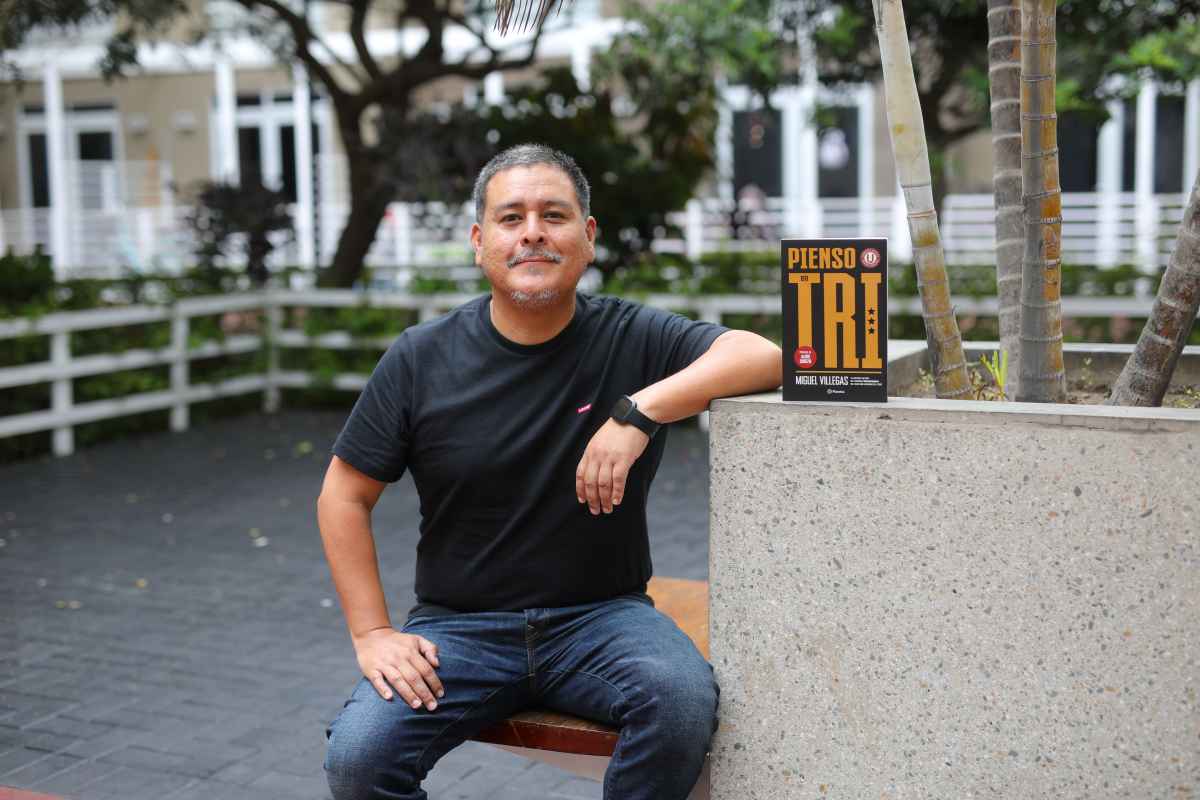 Miguel Villegas posa junto a "Pienso en Tri", uno de los varios libros que ha escrito sobre Universitario de Deportes.