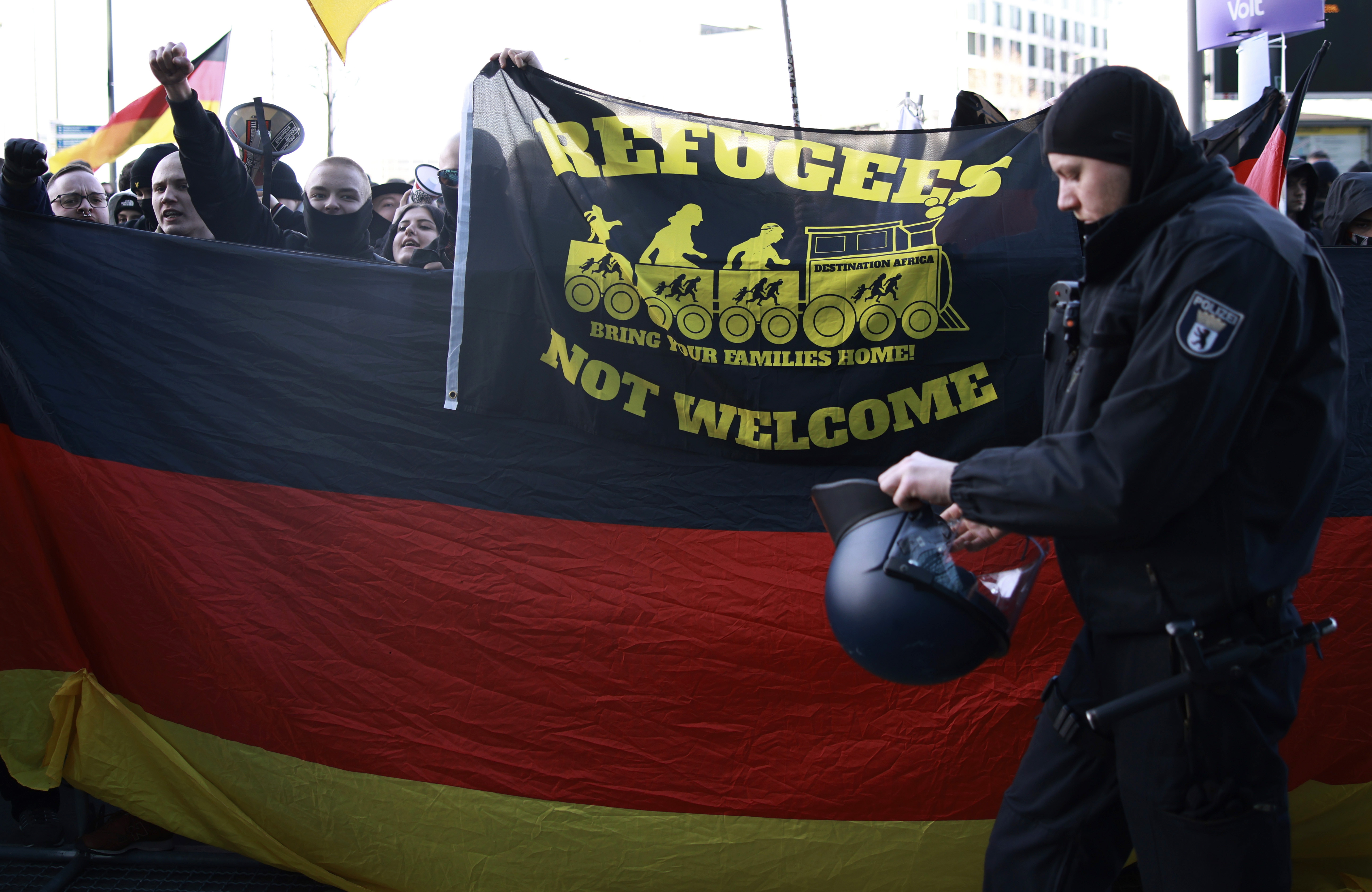 BERLIN (Germany), 22/02/2025.- A police officer walks past participants shouting slogans and displaying a flag and banner during a demonstration by right-wing protesters against 'left-wing extremism' in Berlin, Germany, 22 February 2025. (Protestas, Alemania) EFE/EPA/CLEMENS BILAN