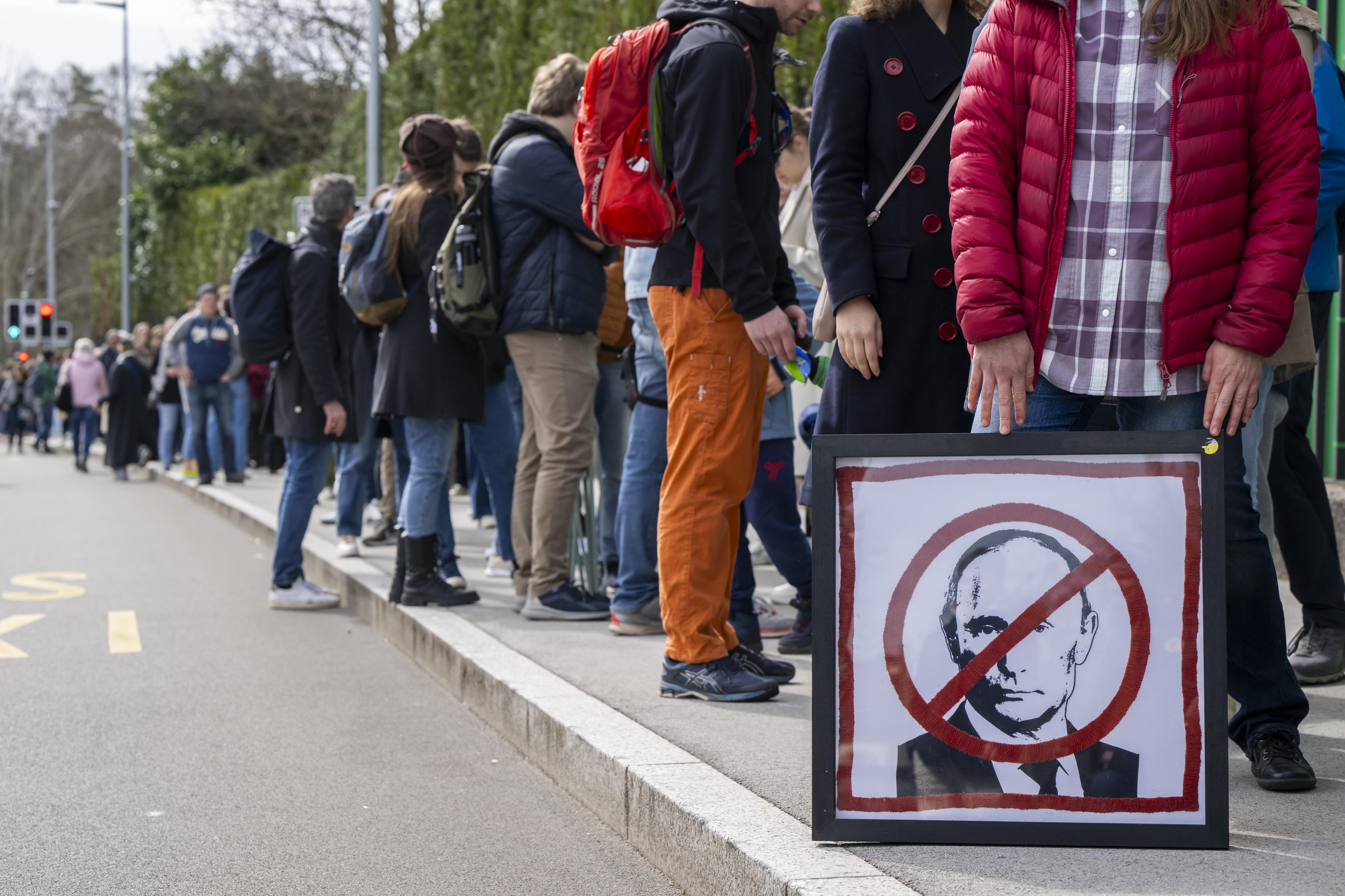 Geneva (Switzerland), 17/03/2024.- A protester holds a placard with a crossed-out picture of Russian President Vladimir Putin, as Russians living in Switzerland gather to protest with the slogan 'Noon against Putin', in front of the Permanent Mission of the Russian Federation to the United Nations, in Geneva, Switzerland, 17 March 2024. Opponents of the regime were called to vote on 17 March at 12:00 noon, on the last day of voting in the Russian presidential election. An incentive to vote on the same day at a specific time in support of Alexei Navalny to protest against his death and the war in Ukraine. The Russian Federation Council has scheduled presidential elections for 17 March 2024. Voting will last three days: March 15, 16 and 17. Four candidates registered by the Central Election Commission of the Russian Federation are vying for the post of head of state: Leonid Slutsky, Nikolai Kharitonov, Vladislav Davankov and Vladimir Putin. (Elecciones, Protestas, Rusia, Suiza, Ucrania, Ginebra) EFE/EPA/MARTIAL TREZZINI