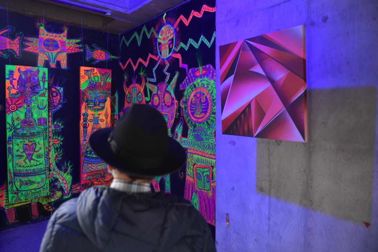 Un hombre viendo una pared pintada con colores de neón