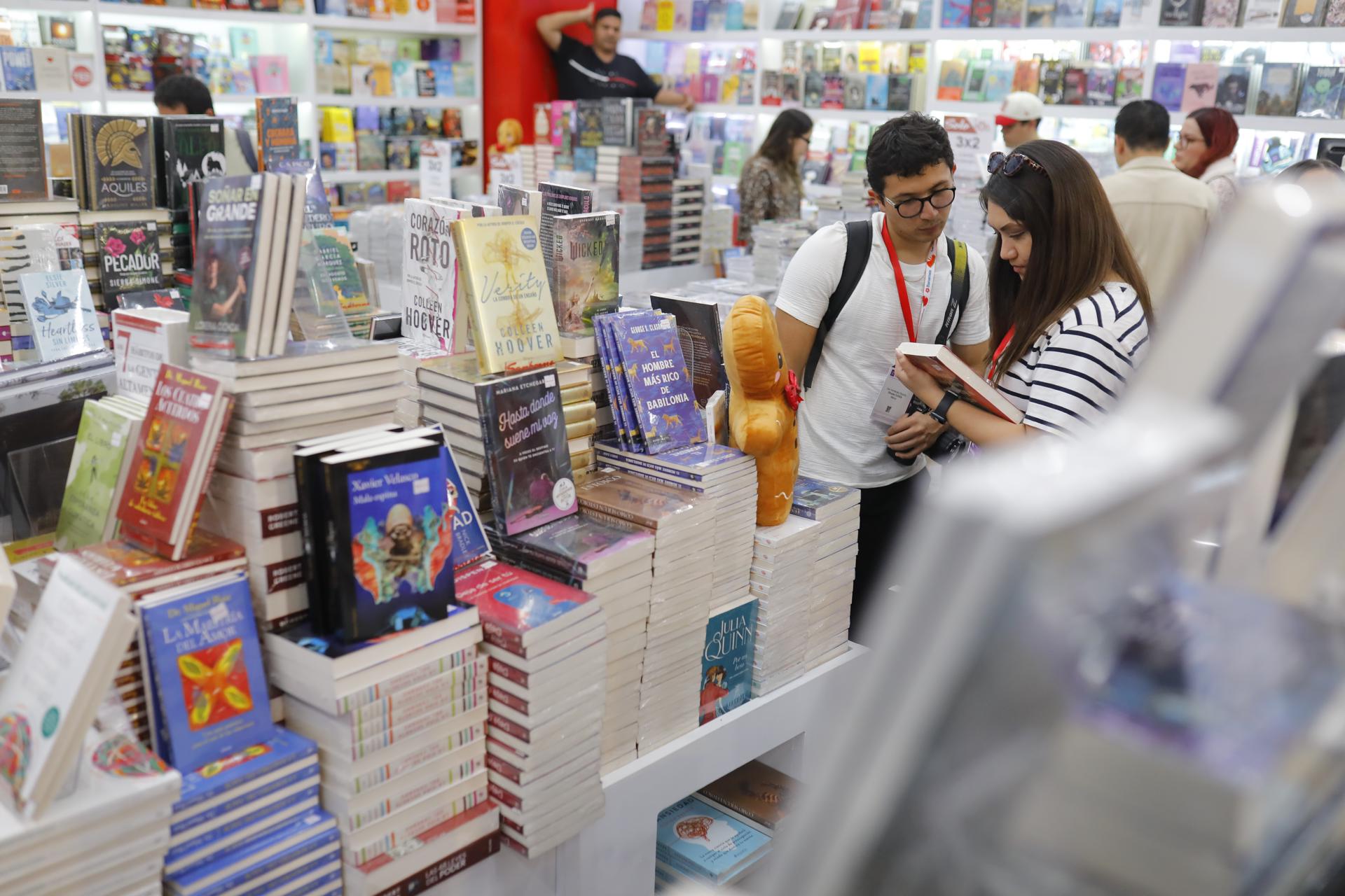 MEX148. GUADALAJARA (MÉXICO), 01/12/2025.- Personas observan un libro durante la 39 edición de la Feria Internacional del Libro de Guadalajara (FIL) este lunes, en Guadalajara (México). Más de 18 millones de mexicanos, es decir, el 8,5 % de los adultos en México, compraron un libro en los últimos 12 meses, según un estudio de NielsenIQ difundido este lunes. EFE/ Francisco Guasco
