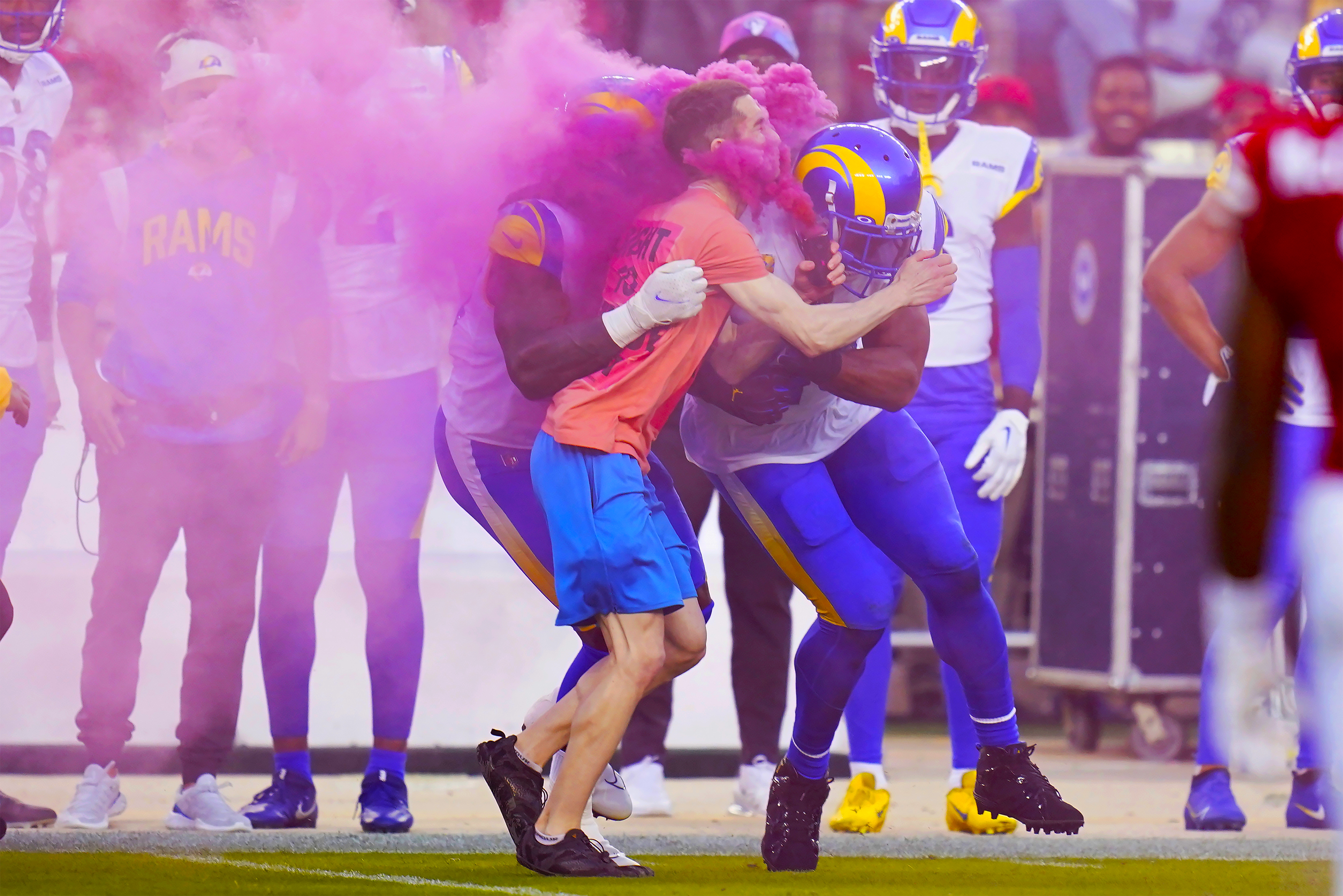 Un manifestante es golpeado por el ala defensiva de los Rams de Los Ángeles, Takkarist McKinley, en el centro a la izquierda, y el apoyador Bobby Wagner durante la primera mitad de un partido de fútbol americano de la NFL entre los 49ers de San Francisco y los Rams en Santa Clara, California, el lunes 3 de octubre de 2022.