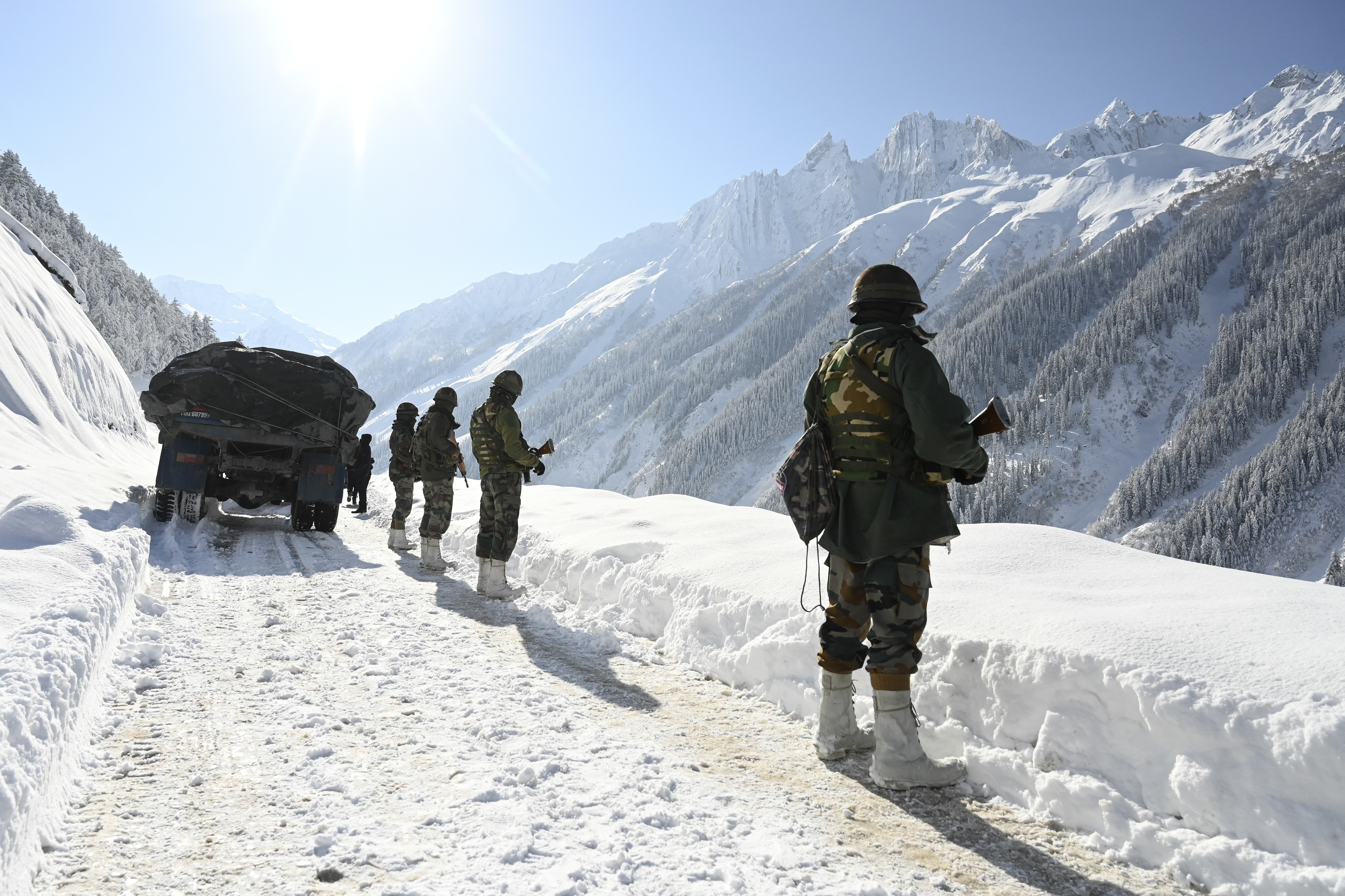 (FILES) Indian army soldiers walk along a road near Zojila mountain pass that connects Srinagar to the union territory of Ladakh, bordering China on February 28, 2021.