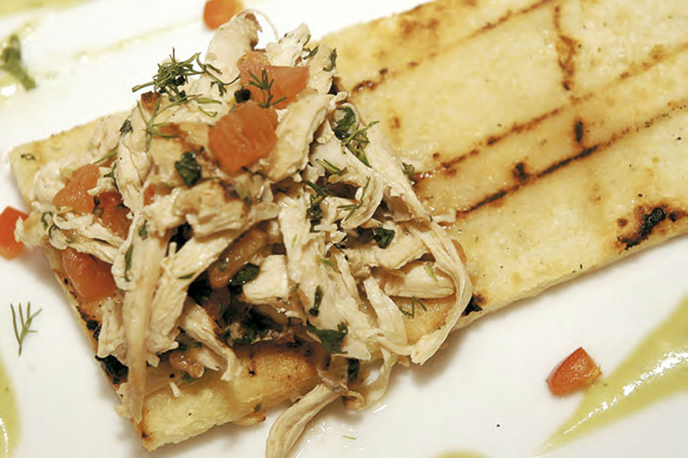 Pollo desmechado sobre galleta de maíz con salsa de aguacate
