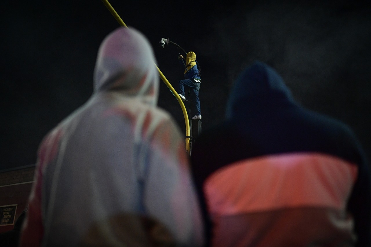 Dos hombres viendo a otro montado en un semáforo.