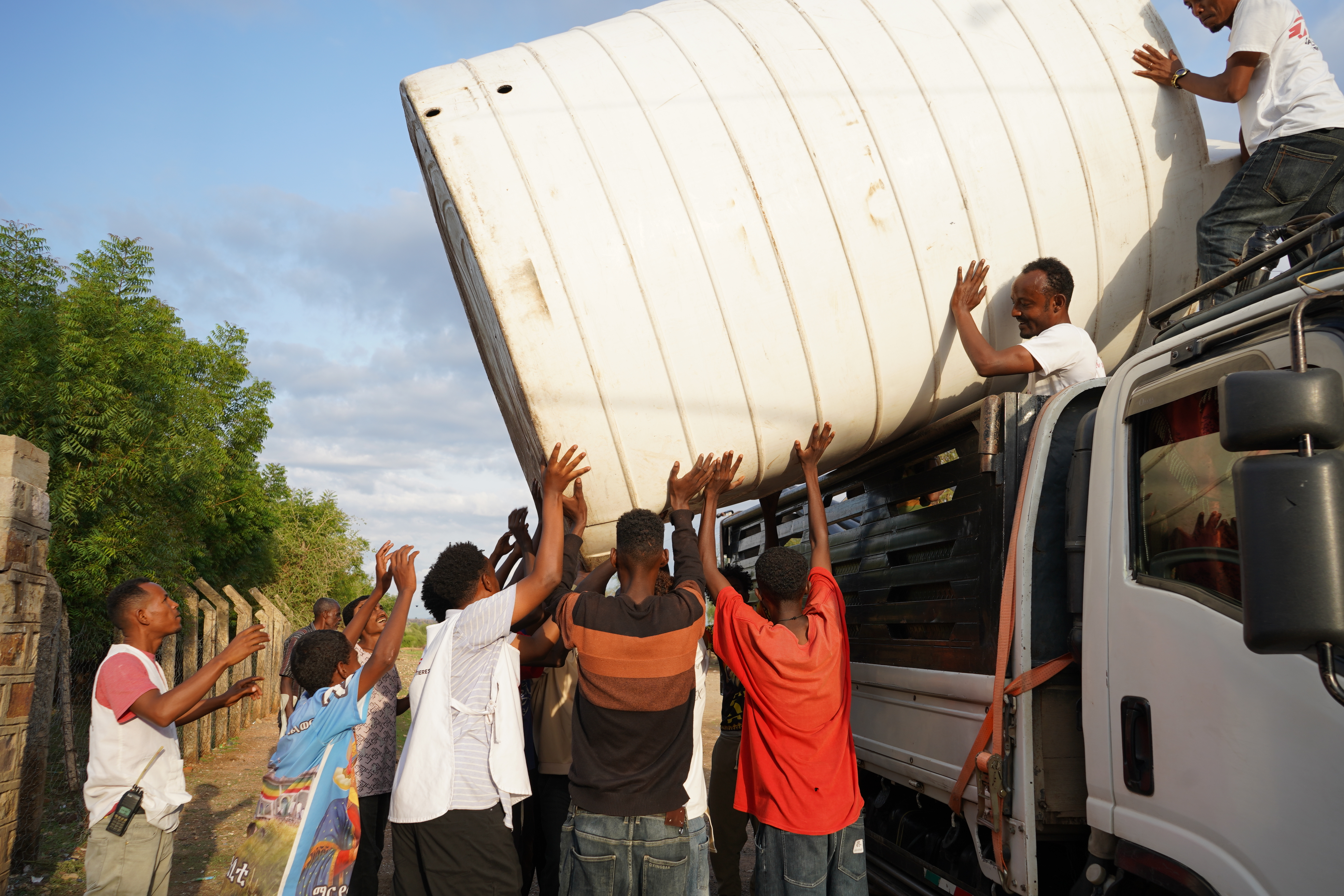 Personal de MSF y miembros de la comunidad instalan un tanque de agua en el campamento de desplazados internos de TVET en Sheraro, región de Tigray, Etiopía.