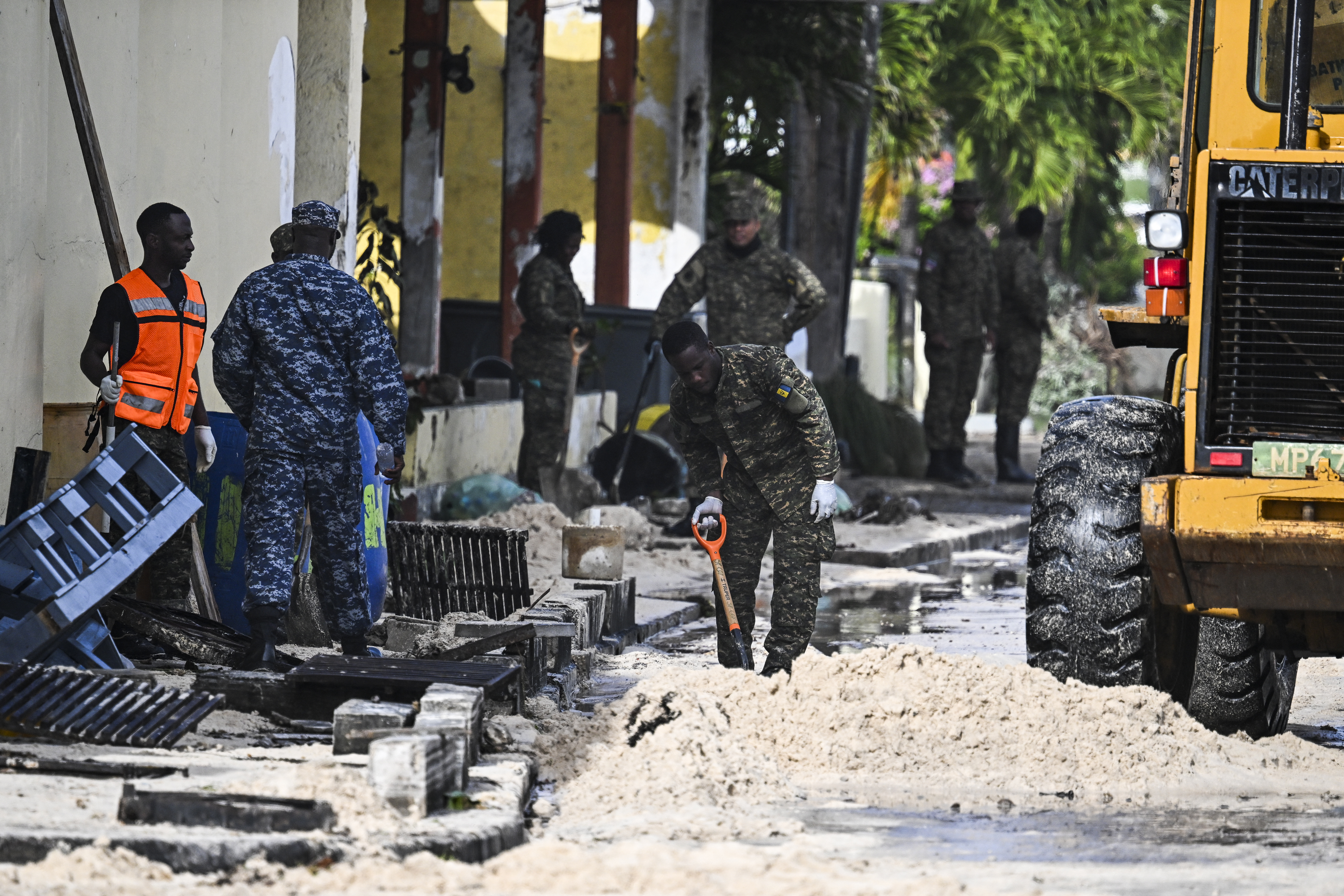 Miembros de las Fuerzas Armadas Nacionales de Barbados limpian de arena una calle inundada por el agua del mar.