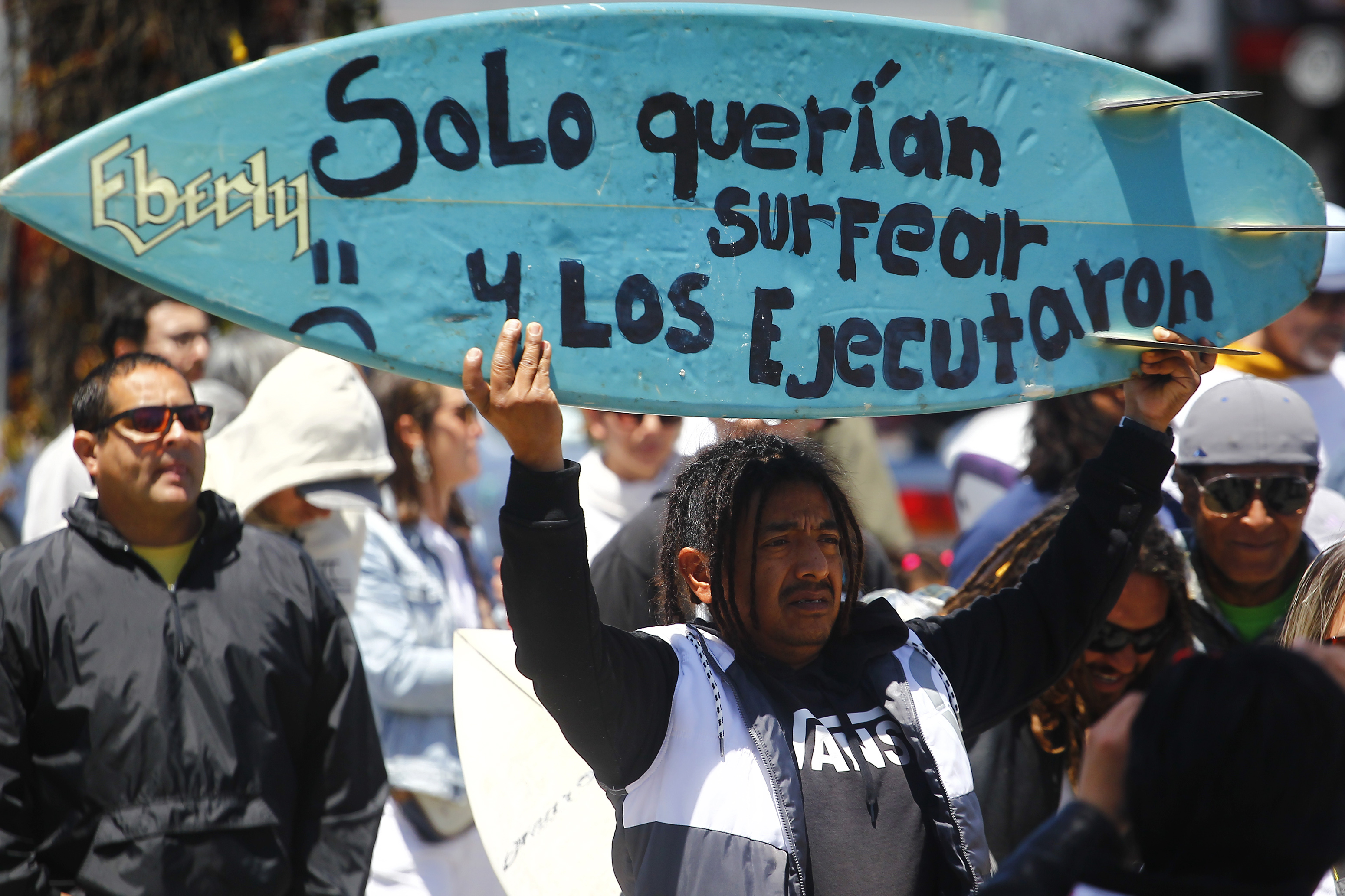 -FOTODELDÍA- MEX6784. ENSENADA (MÉXICO), 05/05/2024.- Un hombre sostiene una tabla de surf durante una manifestación para exigir justicia por el asesinato de tres surfistas extranjeros este domingo, en la ciudad de Ensenada (México). Autoridades mexicanas señalaron este domingo que el probable homicidio de los tres surfistas extranjeros cerca de Ensenada (Baja California), en el noroeste de México, fue por el robo de un vehículo en el que viajaban y que los cuerpos presentan "orificio por arma de fuego en la cabeza". EFE/Alejandro Zepeda