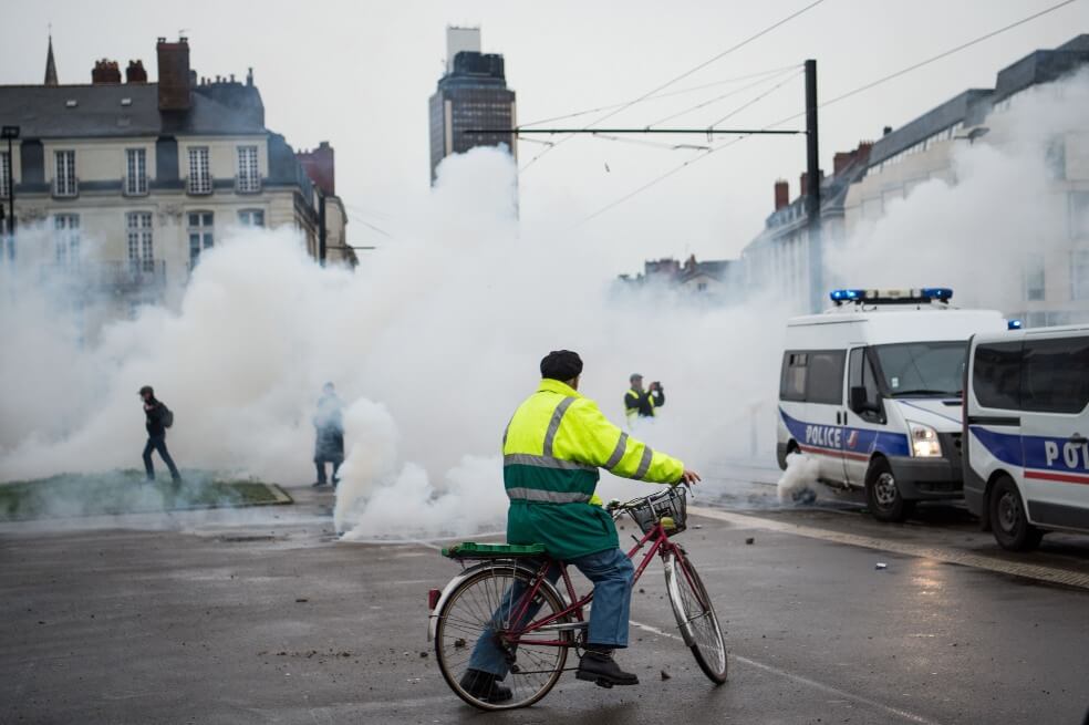 Un ciclista observa los gases durante una jornada de protesta contra la reforma pensional en París.  / AFP