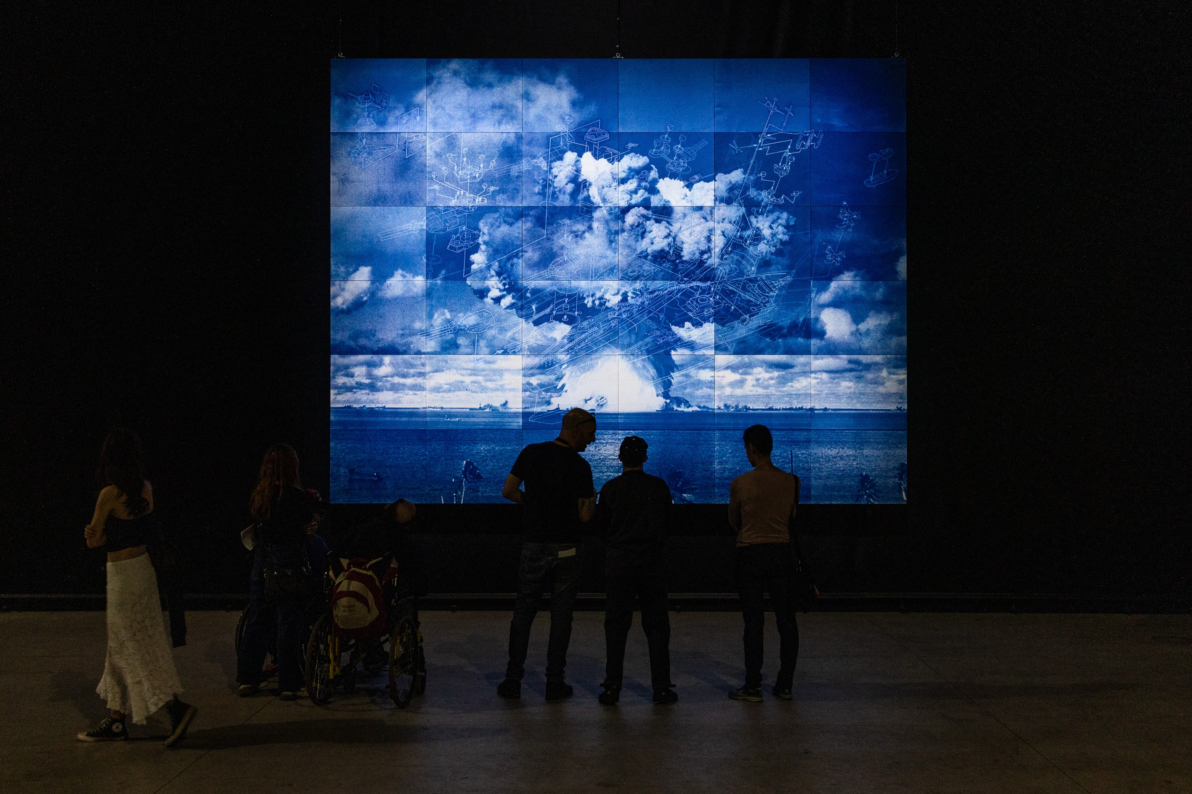 Personas observan una obra de arte contemporáneo inspirada en una fotografía de explosión nuclear, hecha por el artista japonés Yukinori Yanagi.