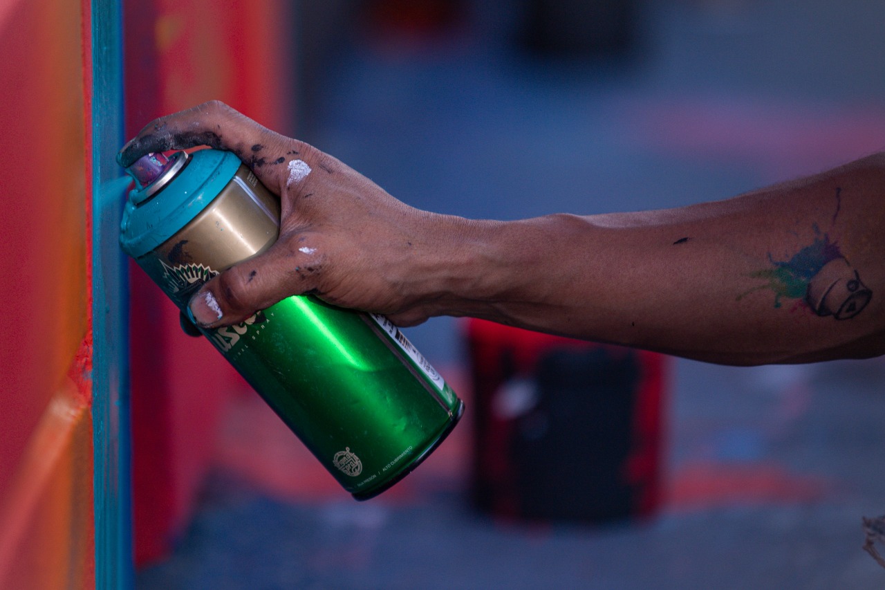 La mano de una persona aplicando un aerosol en una pared.