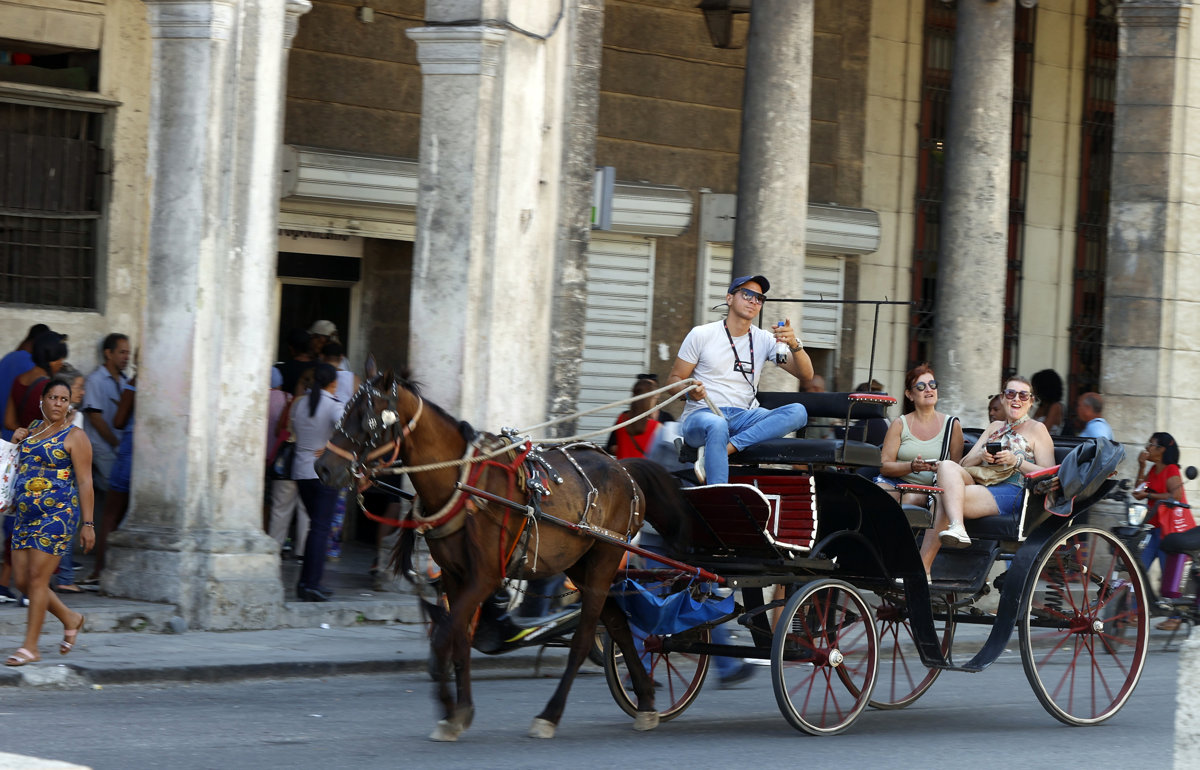 AME1213. LA HABANA (CUBA), 28/04/2024.- Dos turistas pasean en un coche alado por un caballo, el 23 de abril de 2024, en La Habana (Cuba). El turismo no termina de despegar en Cuba tras la pandemia. Este sector estratégico sigue lastrado por las débiles cifras de visitantes, las sanciones estadounidenses y la profunda crisis que sufre el país, que perjudica al servicio y la experiencia. La celebración del 2 y al 5 de mayo de la Feria Internacional de Turismo (FITCuba), la principal cita del sector en la isla, va a poner de relieve estos retos, las apuestas para 2024 y la dependencia nacional de esta industria, como bosqueja esta radiografía del sector. EFE/ Ernesto Mastrascusa