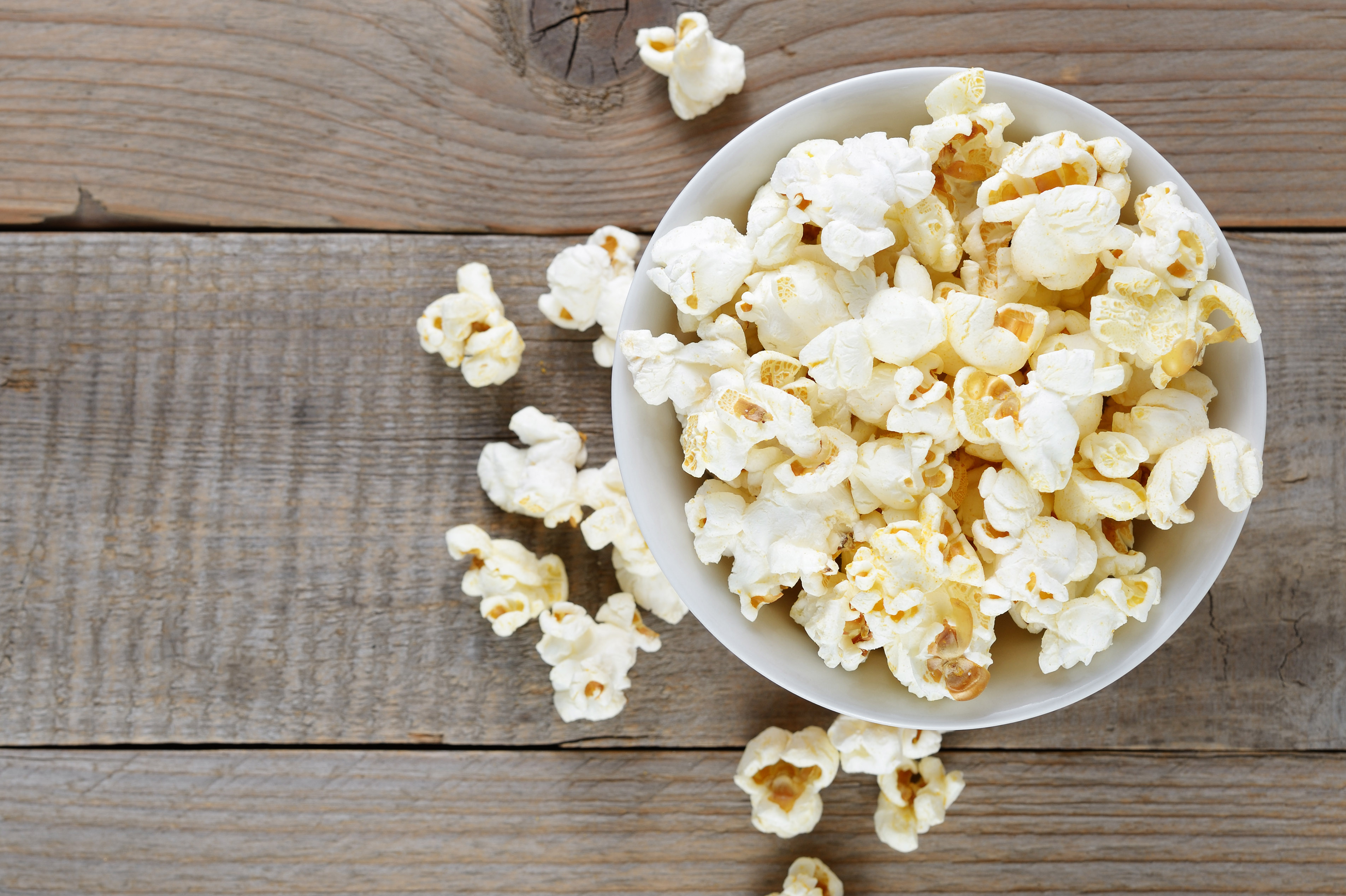 Popcorn in bowl on wooden table