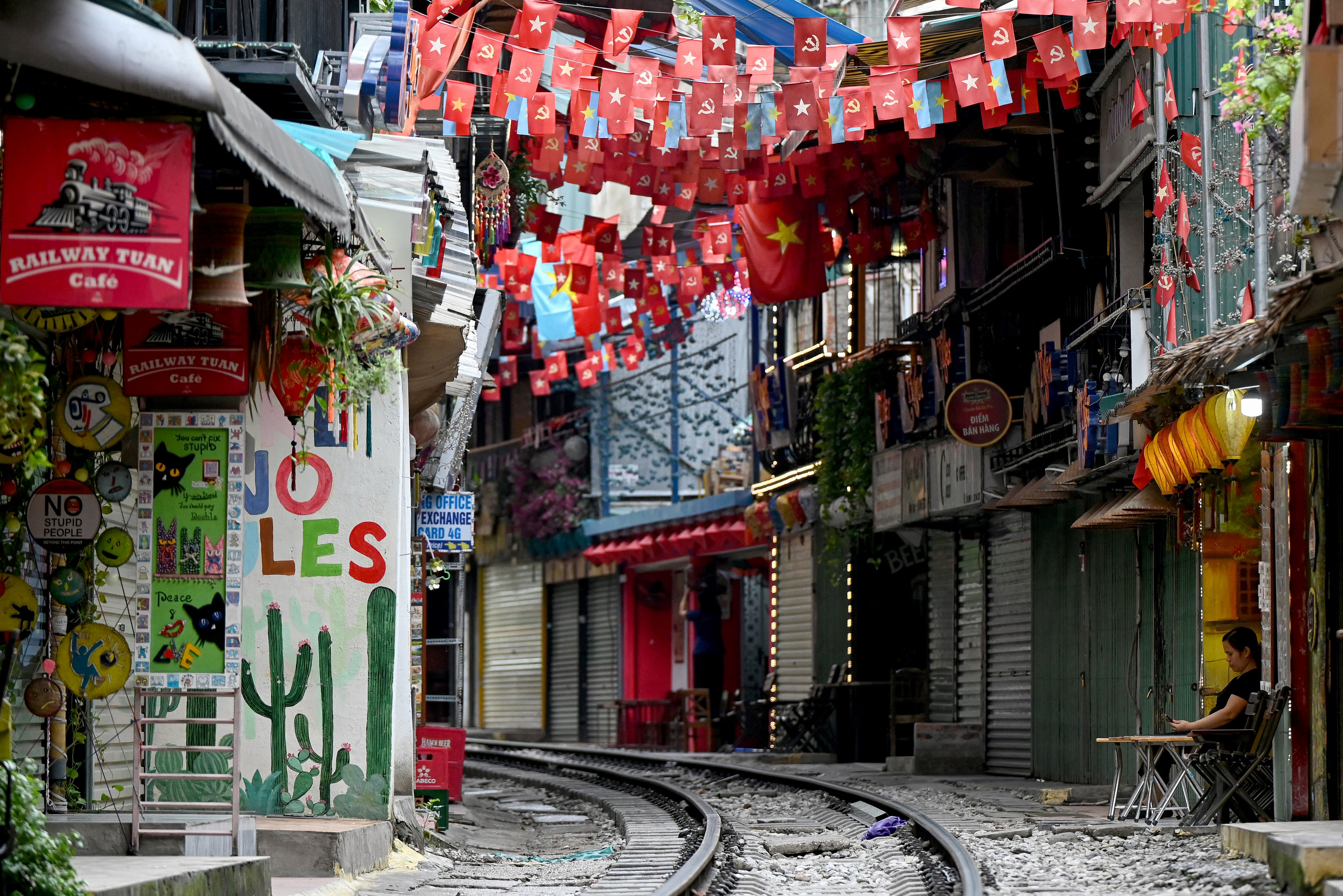 This photo taken on August 18, 2025 shows a woman (R) sitting in front of a cafe along the railway tracks in central Hanoi.