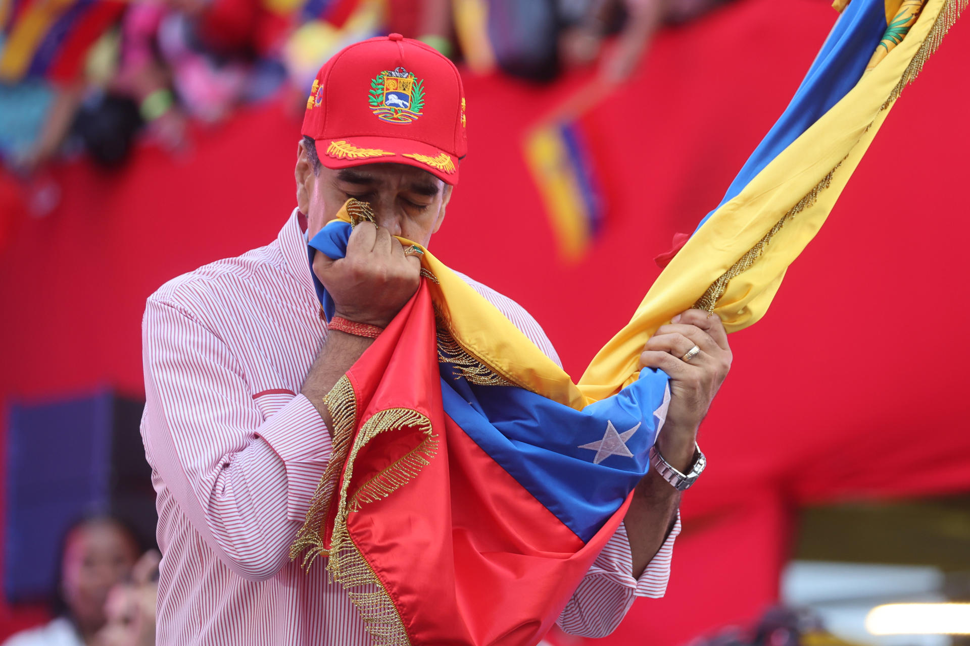 AME4714. CARACAS (VENEZUELA), 01/12/2025.- El presidente de Venezuela, Nicolás Maduro, besa una bandera durante una movilización este lunes, en Caracas (Venezuela). Maduro dijo que el poder de su país se sustenta en el pueblo, en sus fusiles y su decisión de construir la patria, en momentos en que ha escalado la tensión con EE.UU. por cuenta del despliegue militar que mantiene en el Caribe y sus advertencias sobre el espacio aéreo venezolano que han derivado en una ola de cancelaciones de vuelos. EFE/ Miguel Gutiérrez