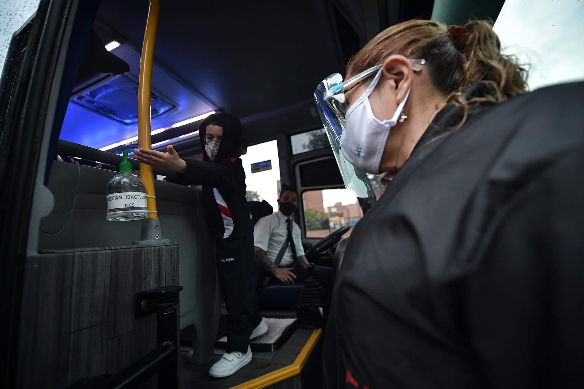 Un niño aplicándose gel antibacterial al subirse a la ruta.