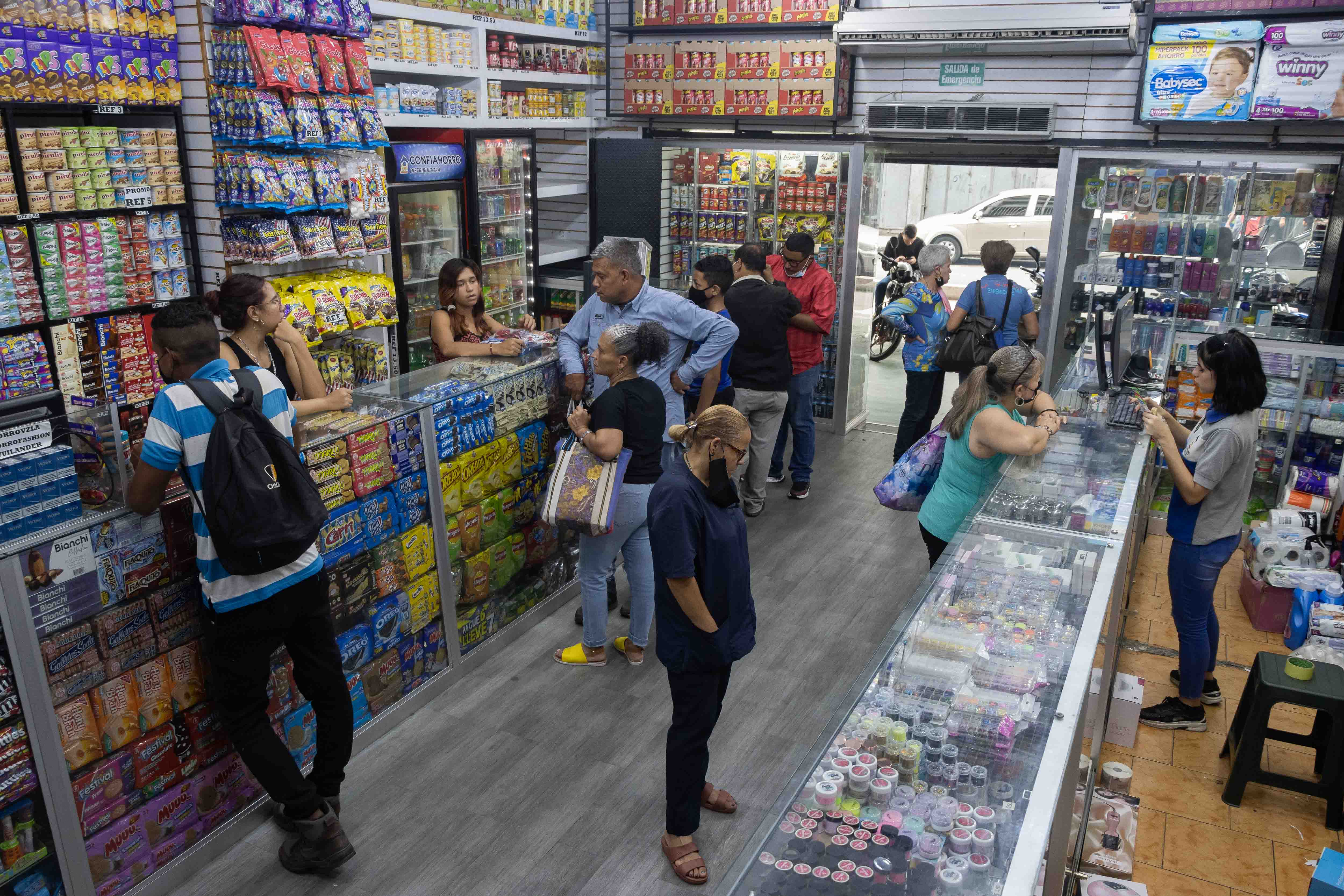 AME9794. CARACAS (VENEZUELA), 16/05/2022.- Personas acuden a comprar a una tienda, el 11 de mayo de 2022, en Caracas (Venezuela). Venezuela, en plena recuperación económica tras siete años de caída, prevé para este año un crecimiento de entre el 5 y el 8 Venezuela, en plena recuperación económica tras siete años de caída, prevé para este año un crecimiento de entre el 5 y el 8 %, según expertos, que consideran que la mejora será irregular en los diferentes sectores y difícil de mantener en el tiempo. La actividad económica, que se contrajo un 80 % desde 2013, responde positivamente a un cambio en las políticas del Gobierno, que se ha abierto al dólar, tras años de rechazo a la divisa, y a inversionistas privados, a la vez que redujo los controles y las intervenciones a empresas, según explicó a Efe el economista Giorgio Cunto. EFE/ Ronald Peña