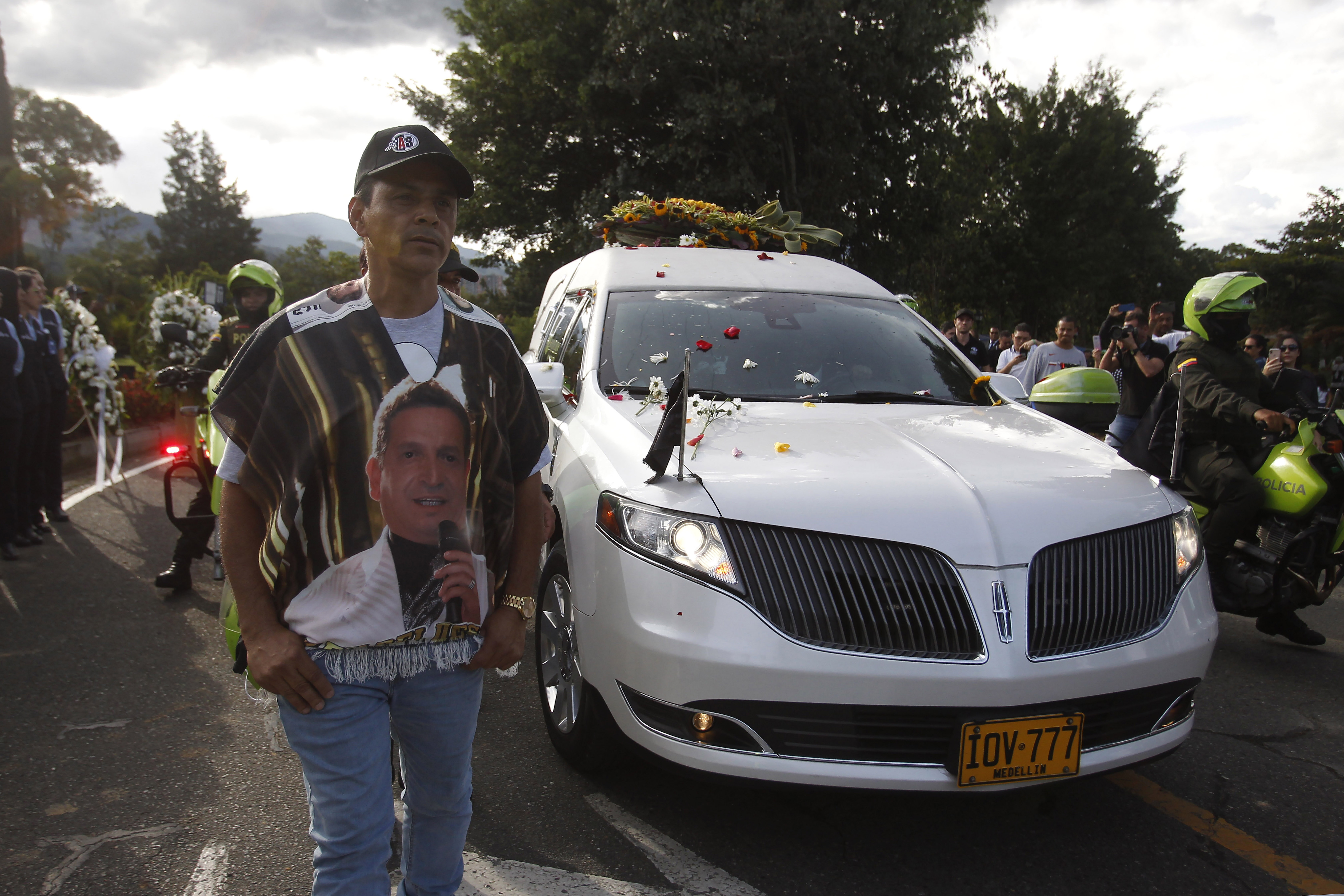AME6426. MEDELLÍN (COLOMBIA), 30/07/2022.- Seguidores del cantante colombiano Darío Gómez acompañan la caravana con el cortejo fúnebre que lleva el cuerpo del artista rumbo a su entierro en el cementerio Campos de Paz, hoy, en Medellín (Colombia). Cientos de fanáticos se volcaron a las calles de Medellín para acompañar por última vez al cortejo fúnebre que traslada el cuerpo del cantante Darío Gómez rumbo a la iglesia Santa Gema, donde se realizarán las exequias de manera privada por disposición de la familia y luego de varios días espontáneos homenajes de fanáticos y la ciudadanía en general. La muerte del compositor y cantante colombiano de música popular Darío Gómez, de 71 años de edad, ha provocado una oleada de reacciones de toda la sociedad en Colombia, donde es considerado un ícono y el máximo exponente del género popular. EFE/ Luis Eduardo Noriega