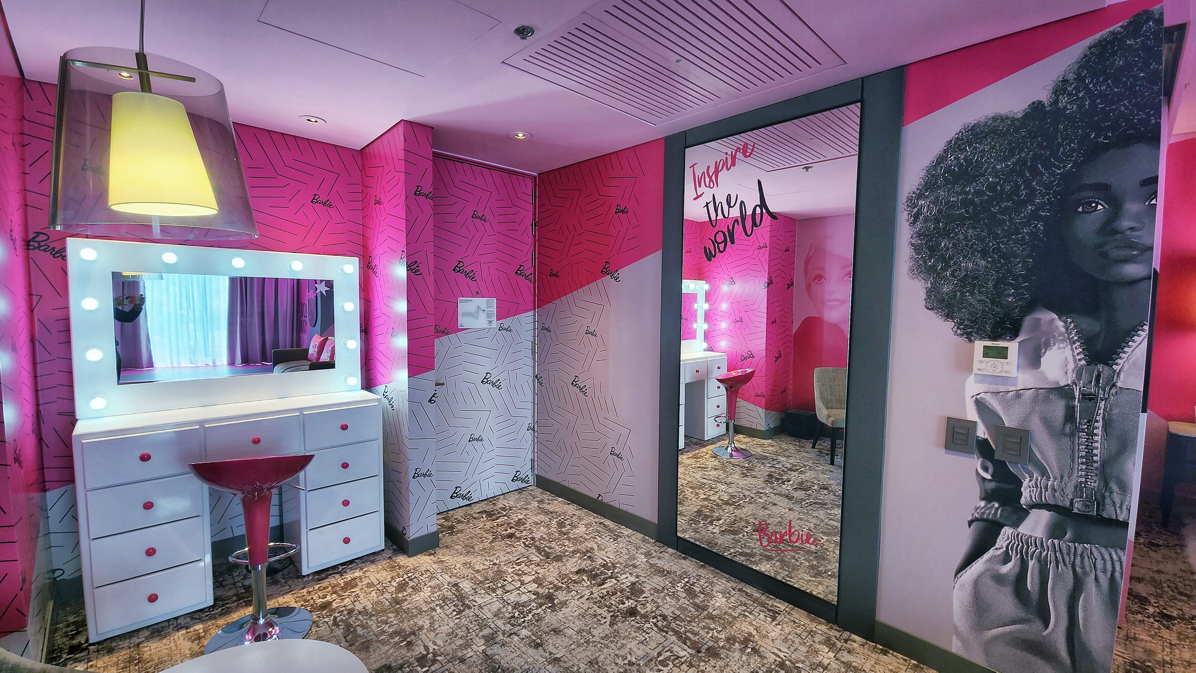 Los tonos rosados adornan la pared junto a imágenes estampadas de Barbie y sus amigos y obras de arte contemporáneas de la icónica muñeca.