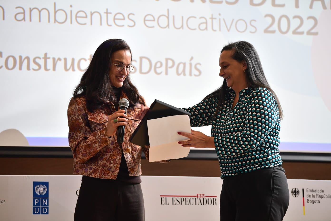 El segundo lugar en la categoría de  Instituciones educativas privadas por su aporte a la construcción de país lo recibió María Fernanda Gaona (a la derecha), en representación del Colegio Mayor Primeros Maestros FUNPES, por su programa Ecosistema Kolibrí. Quien le entregó el reconocimiento fue María Jaramillo (izq.), docente del Departamento de Filosofía e Historia del Derecho de la Pontificia Universidad Javeriana.