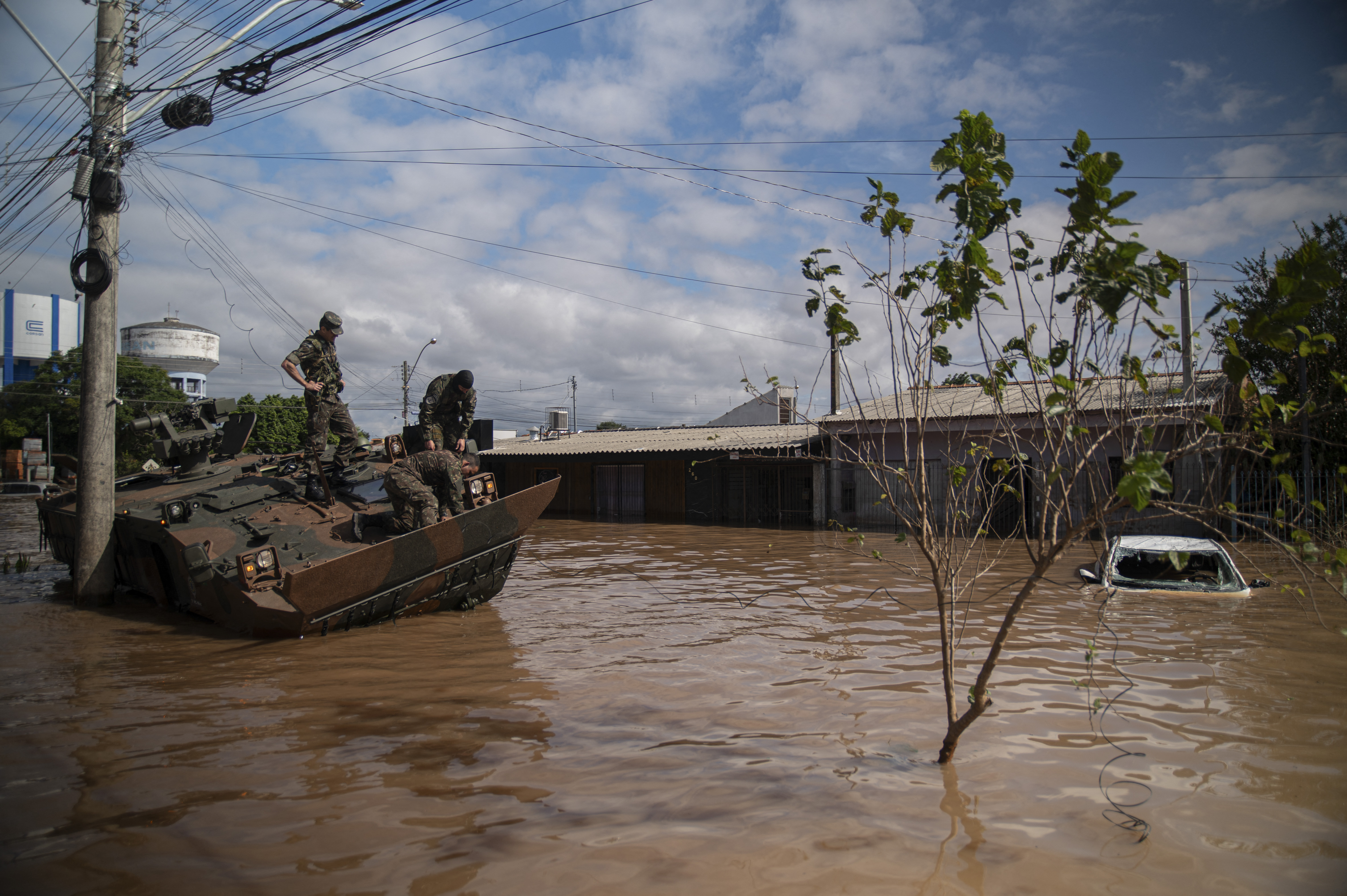 TOPSHOT - Army soldiers observe their damaged vehicle at a flooded street of Eldorado do Sul, Rio Grande do Sul state, Brazil on May 9, 2024.