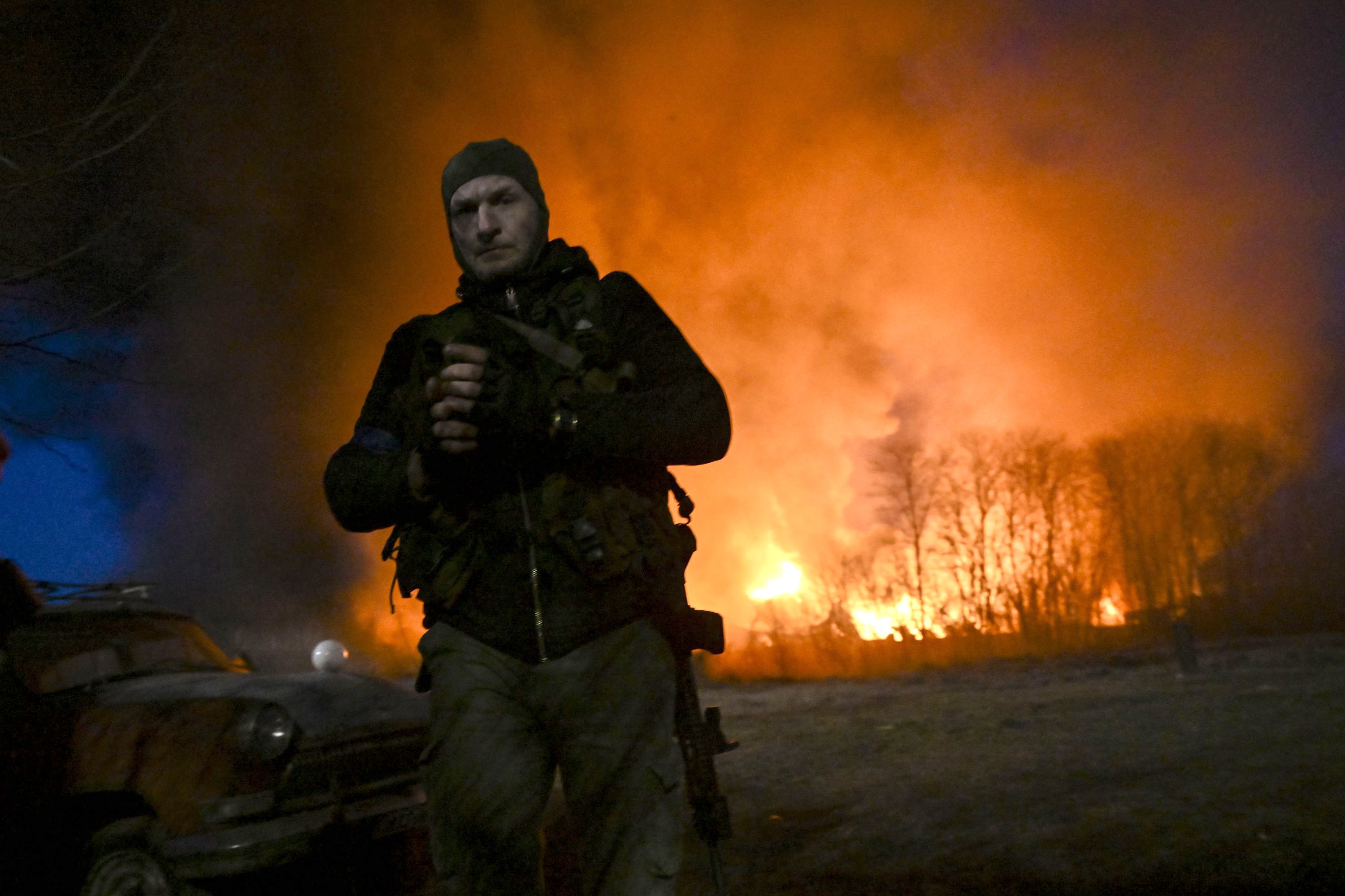Un militar ucraniano mira mientras está de pie frente a un almacén en llamas después de un bombardeo en Kyiv el 17 de marzo de 2022.  Los primeros bombardeos rusos mataron a 21 civiles. Tres semanas después de su devastadora invasión, las fuerzas rusas también fueron acusadas de bombardear un teatro que albergaba a muchos civiles y que estaba marcado con la palabra "niños". Aris Messinis / AFP