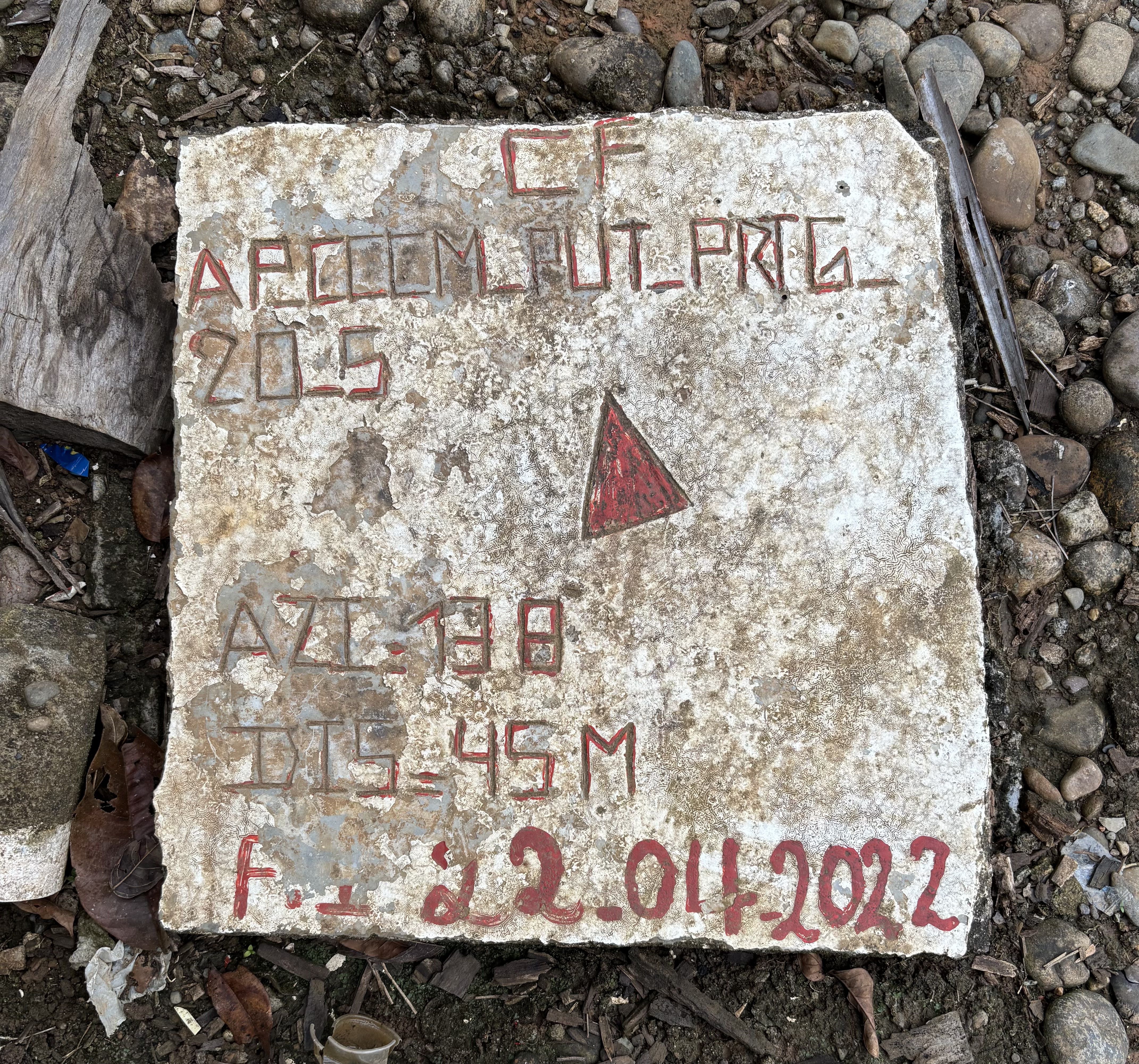 Esta placa de cemento se ubica en el suelo, a la entrada del resguardo Alpamanga. La flecha roja señala la dirección en la que se encontraban las minas en un área de 45 metros. También indica la fecha de revisión por el equipo de desminado.