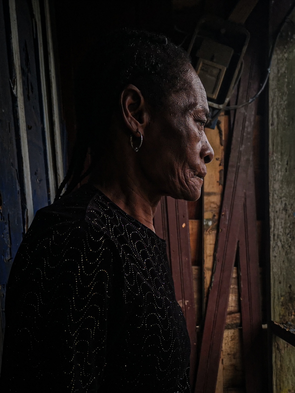 Una mujer adulta mayor, vestida con una blusa negra, posa de perfil