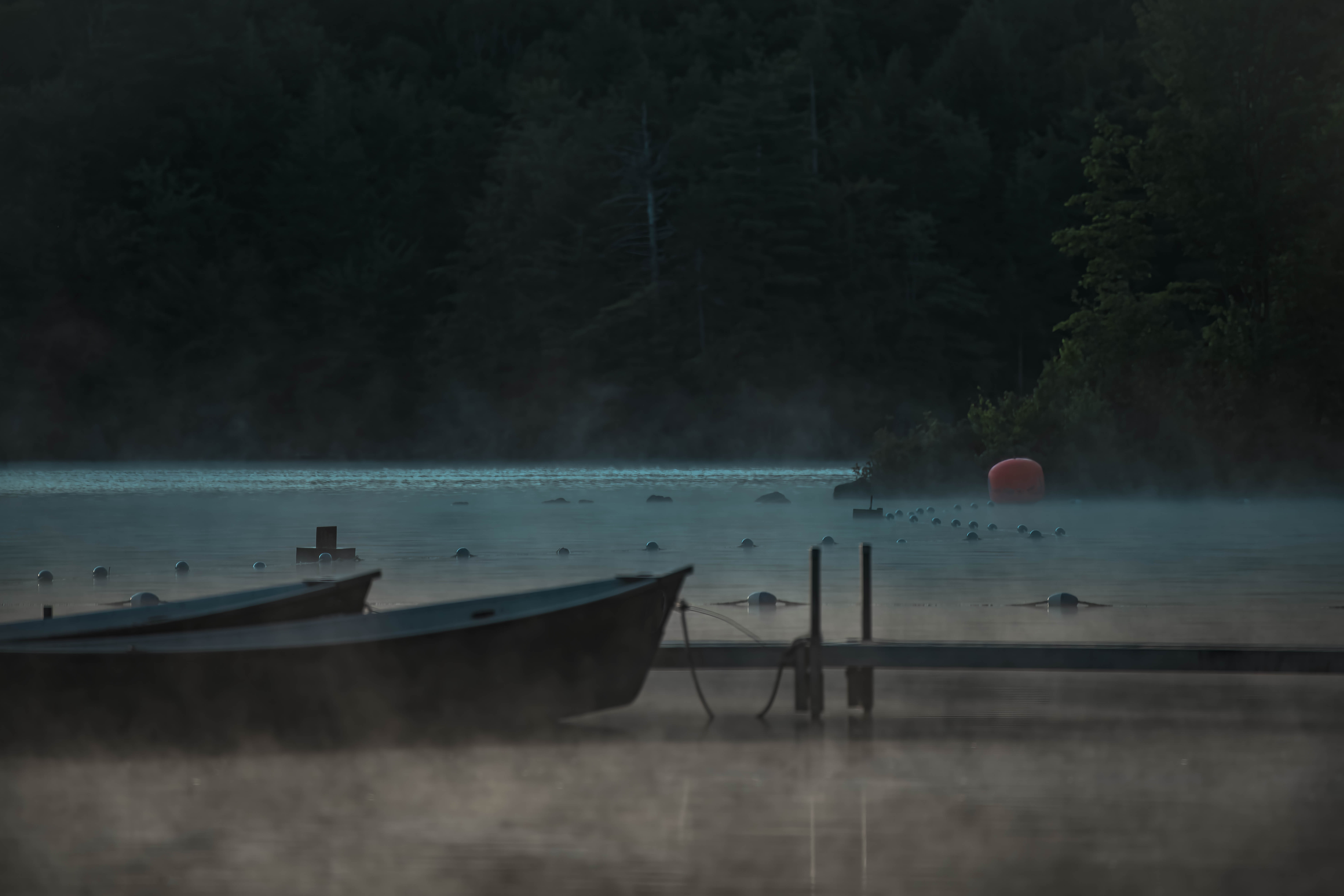 On a lake at dusk, boats and mist
