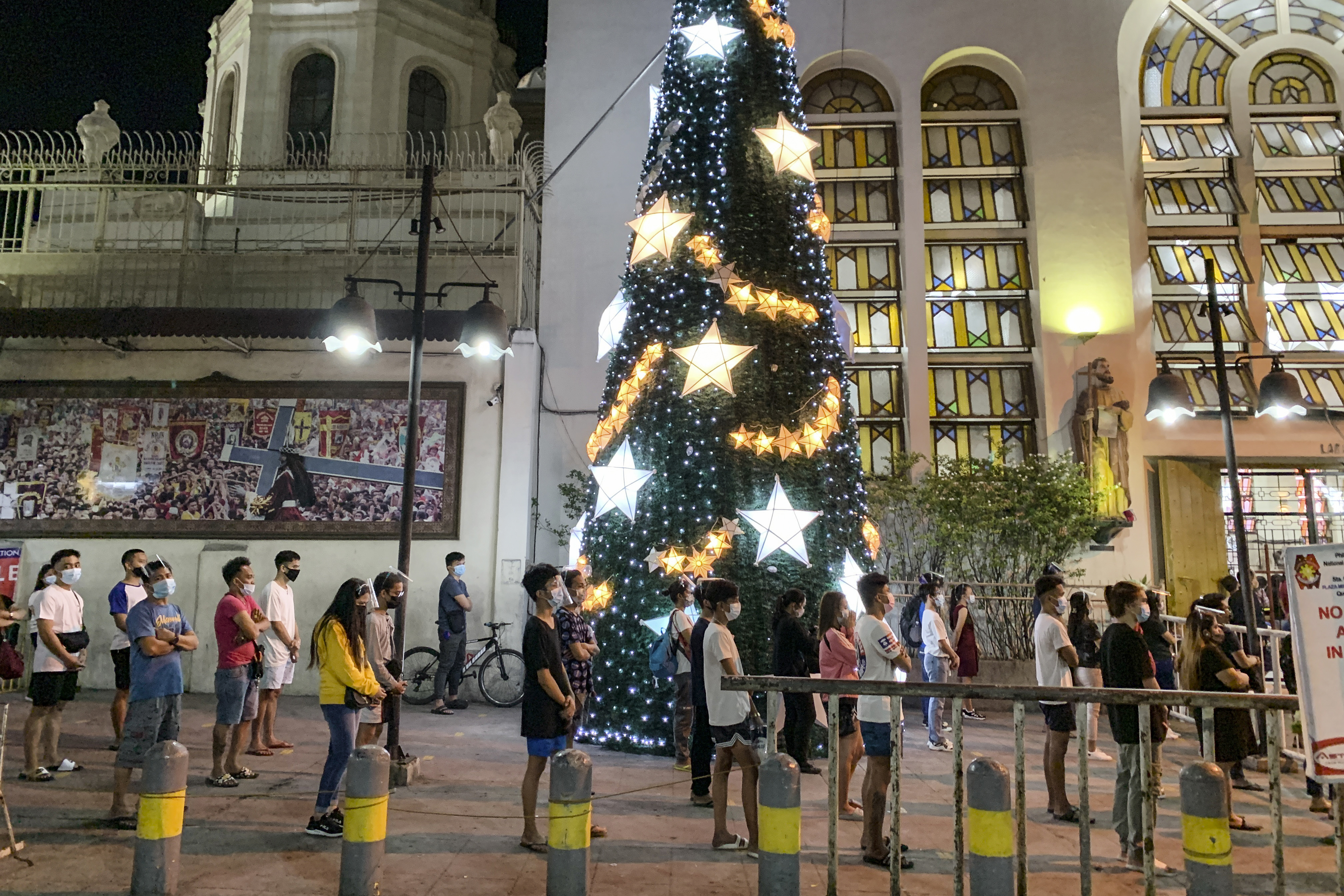 Algunos católicos asisten a una misa de Nochebuena frente a la iglesia de Quiapo en Manila (Filipinas) donde mantienen el distanciamiento social para evitar la propagación del coronavirus.