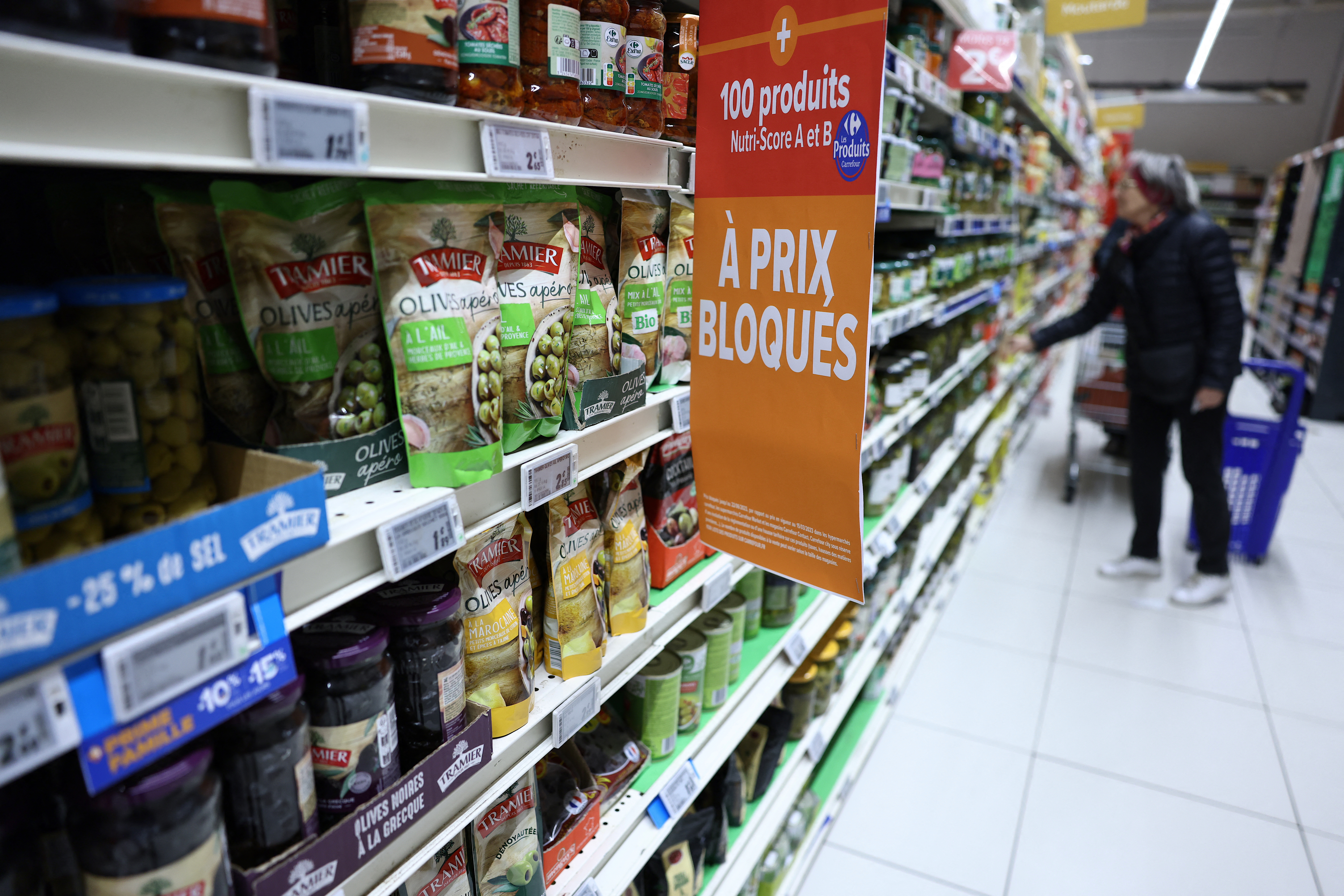 (FILES) A customer looks at food products next to a label which reads as "One hundred goods with blocked prices" at a Carrefour hypermarket in Villeneuve-la-Garenne, in the northern suburbs of Paris, on March 29, 2023.