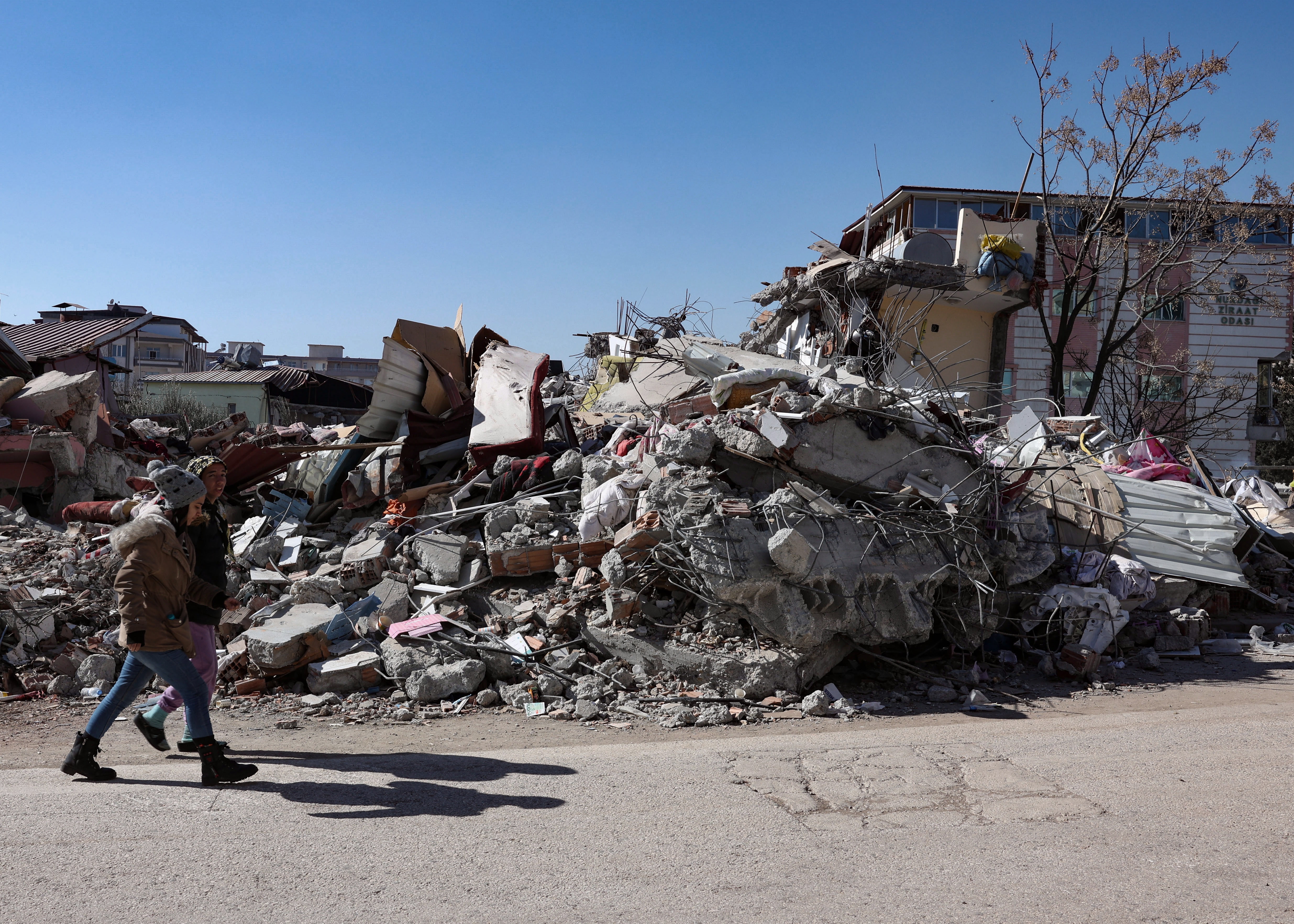 Nurdagi (Turkey), 13/02/2023.- People walk past a collapsed building in the aftermath of an earthquake in Nurdagi, southeastern Turkey, 13 February 2023. More than 30,000 people have died and thousands more were injured after two major earthquakes struck southern Turkey and northern Syria on 06 February. Authorities fear the death toll will keep climbing as rescuers look for survivors across the regions. (Terremoto/sismo, Siria, Turquía, Estados Unidos) EFE/EPA/JOAO RELVAS
