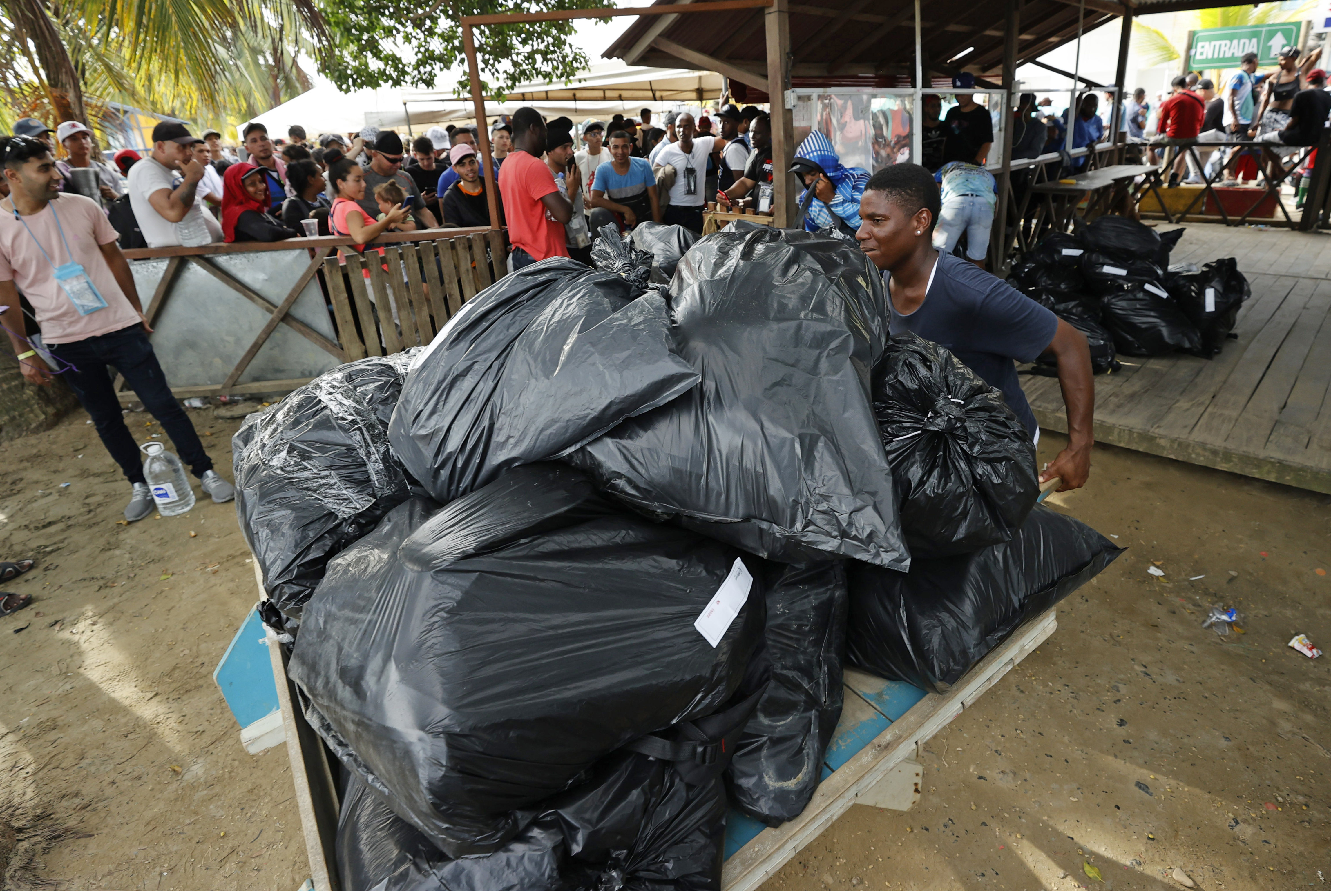 ACOMPAÑA CRÓNICA: COLOMBIA CRISIS MIGRATORIA. AME2685. NECOCLÍ (COLOMBIA), 07/10/2022.- Un joven lleva maletas envueltas en bolsas plásticas hacia un embarcadero, el 6 de octubre de 2022, en Necocli (Colombia). En el pueblo colombiano de Necoclí ya se acostumbraron a que a diario cientos de personas acampen en sus playas a la espera de coger las lanchas que los llevan a la frontera de Panamá en una travesía migratoria hacia EE.UU. que crece cada día y amenaza con "explotar". EFE/ Mauricio Dueñas Castañeda