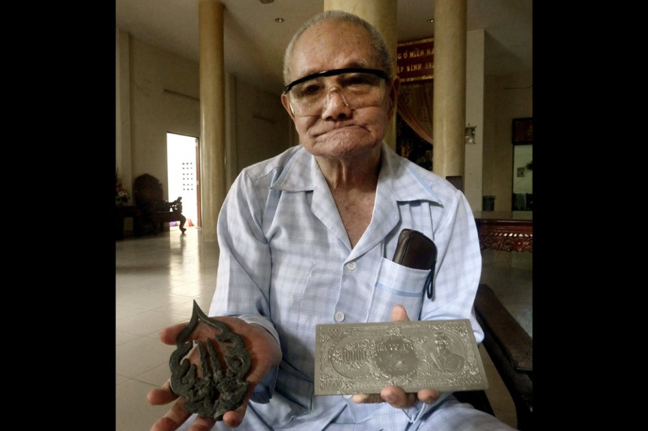 En la imagen, el vietnamita Tran Van Tiep posa en su casa de Ho Chi Minh (antigua Saigón) mientras sostiene dos objetos encontrados durante su búsqueda.