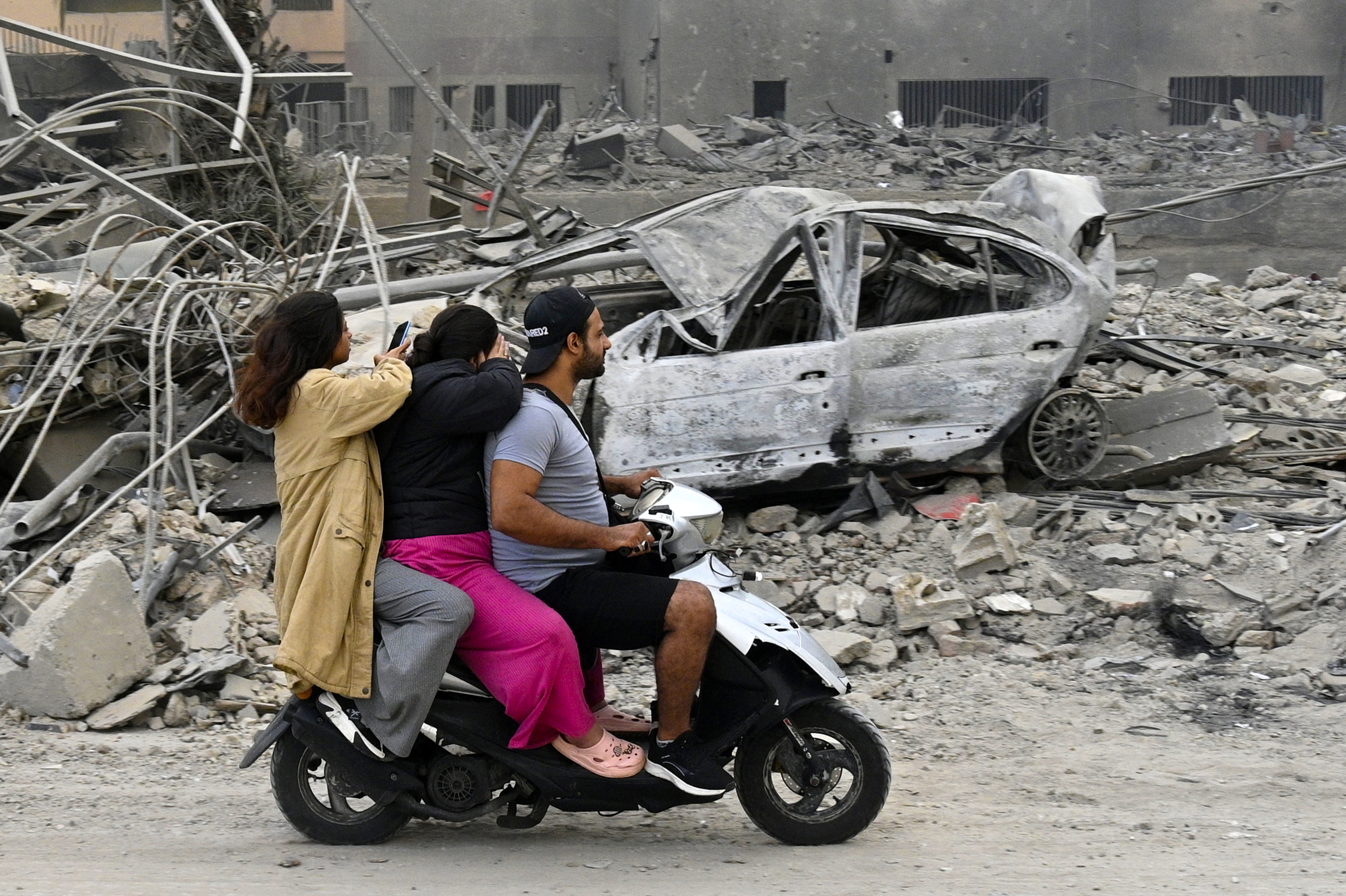 Beirut (Lebanon), 07/10/2024.- People ride a scooter past a razed building following an Israeli airstrike along airport road in the southern suburb of Beirut, Lebanon, 07 October 2024. According to the Lebanese Minister of Health, more than 2,000 people have been killed and more than 9,600 others have been injured in Lebanon since the beginning of the Israeli-Hezbollah conflict. (Líbano, Hizbulá/Hezbolá) EFE/EPA/WAEL HAMZEH