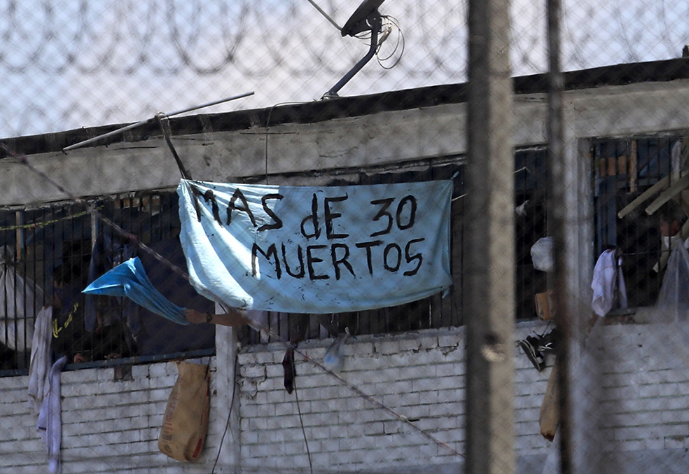 Un grupo de reclusos sostiene una pancarta anunciando, según ellos, un total de 30 muertos en la cárcel La Modelo de Bogotá (foto del 22 de marzo de 2020) / AFP / DANIEL MUNOZ