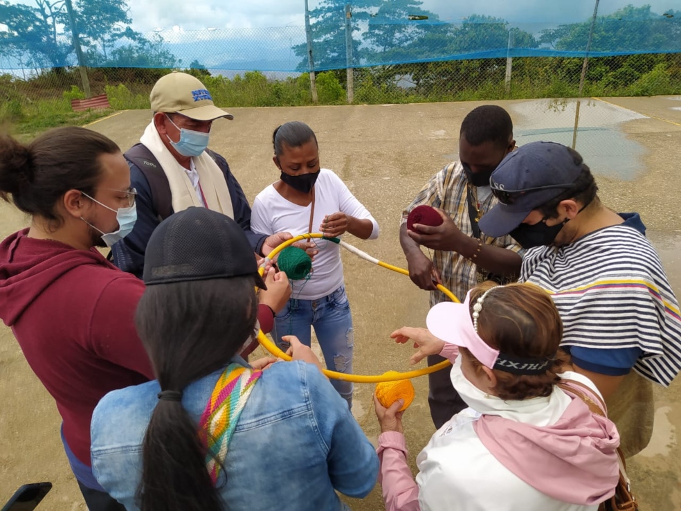 un grupo de personas realizan una actividad grupal: enrrollan hilo al rededor de un aro para hacer una mandala.