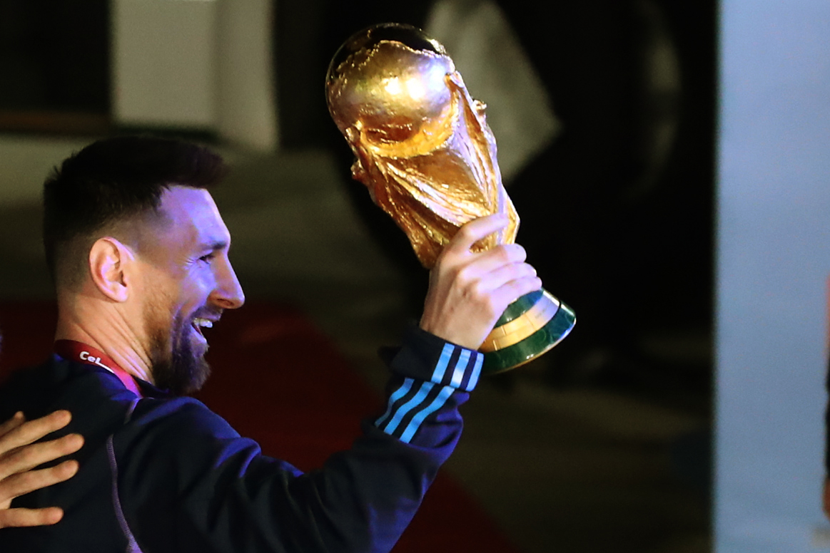 AMDEP9828. EZEIZA (ARGENTINA), 19/12/2022.- Lionel Messi de la selección argentina de fútbol saluda con el trofeo del Mundial de Fútbol Qatar 2022 a su llegada hoy, al Aeropuerto Internacional de Ezeiza a unos 22km de Buenos Aires (Argentina). EFE/ Raúl Martínez