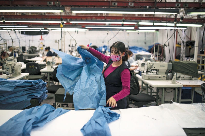 A worker folds protective medical gowns at the National Police clothing factory in Bogota, Colombia, on Saturday, March 28, 2020. Colombia has reported nearly 500 confirmed cases of coronavirus as the government of President Ivan Duque closed borders, suspended incoming flights and imposed a three-week lockdown to try to curb the spread. Photographer: Ivan Valencia/Bloomberg