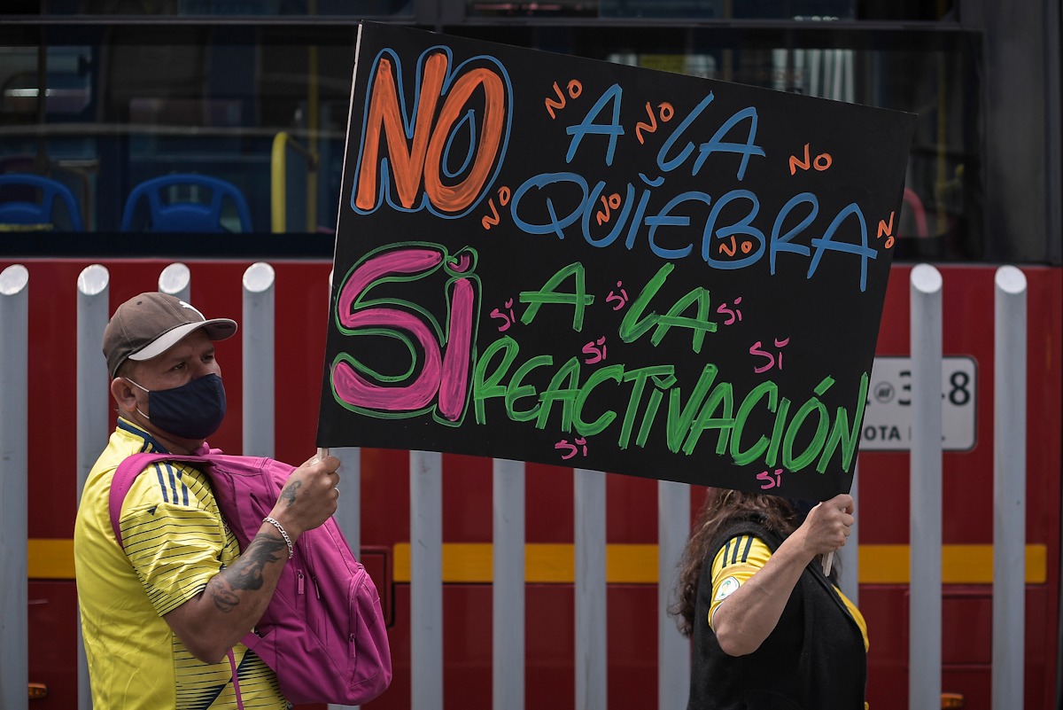 Una mujer y un hombre sostienen un cártel que dice: no a la quiebra si a la reactivación.