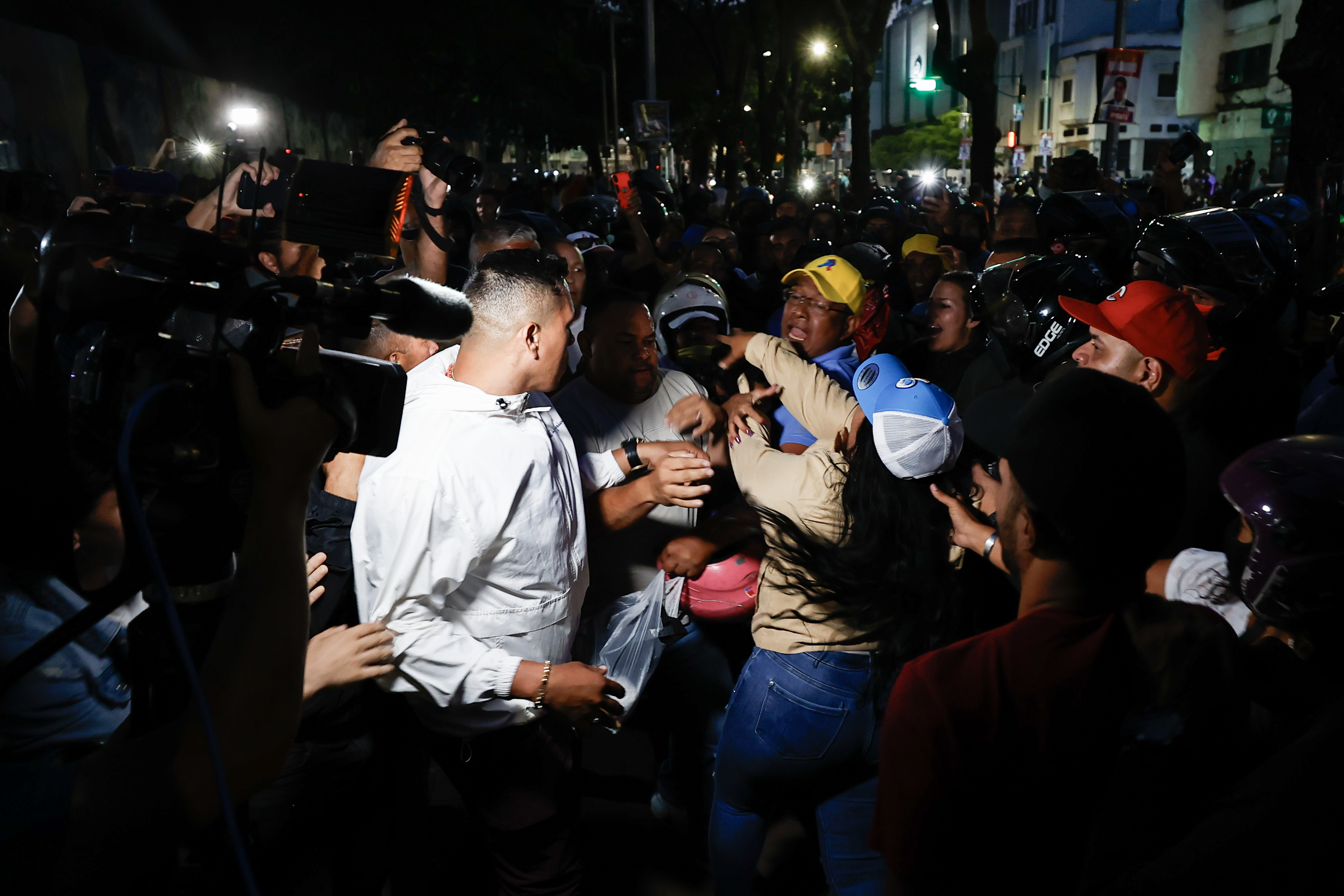 AME5913. CARACAS (VENEZUELA), 28/07/2024.- Seguidores del presidente de Venezuela y candidato a la reelección, Nicolás Maduro, bloquean el acceso a personas que intentan entrar a un centro de votación para el conteo de votos este domingo, en Caracas (Venezuela). Varias decenas de motorizados que se identificaron como chavistas llegaron a un centro de votación en Caracas, donde se encontraban testigos opositores y ciudadanos que esperaban el comienzo del escrutinio de las elecciones presidenciales de este domingo, lo que dio lugar a una confrontación que acabó a golpes, ante la mirada impasible de los policías, que no intervinieron para detener la pelea. EFE/ Henry Chirinos