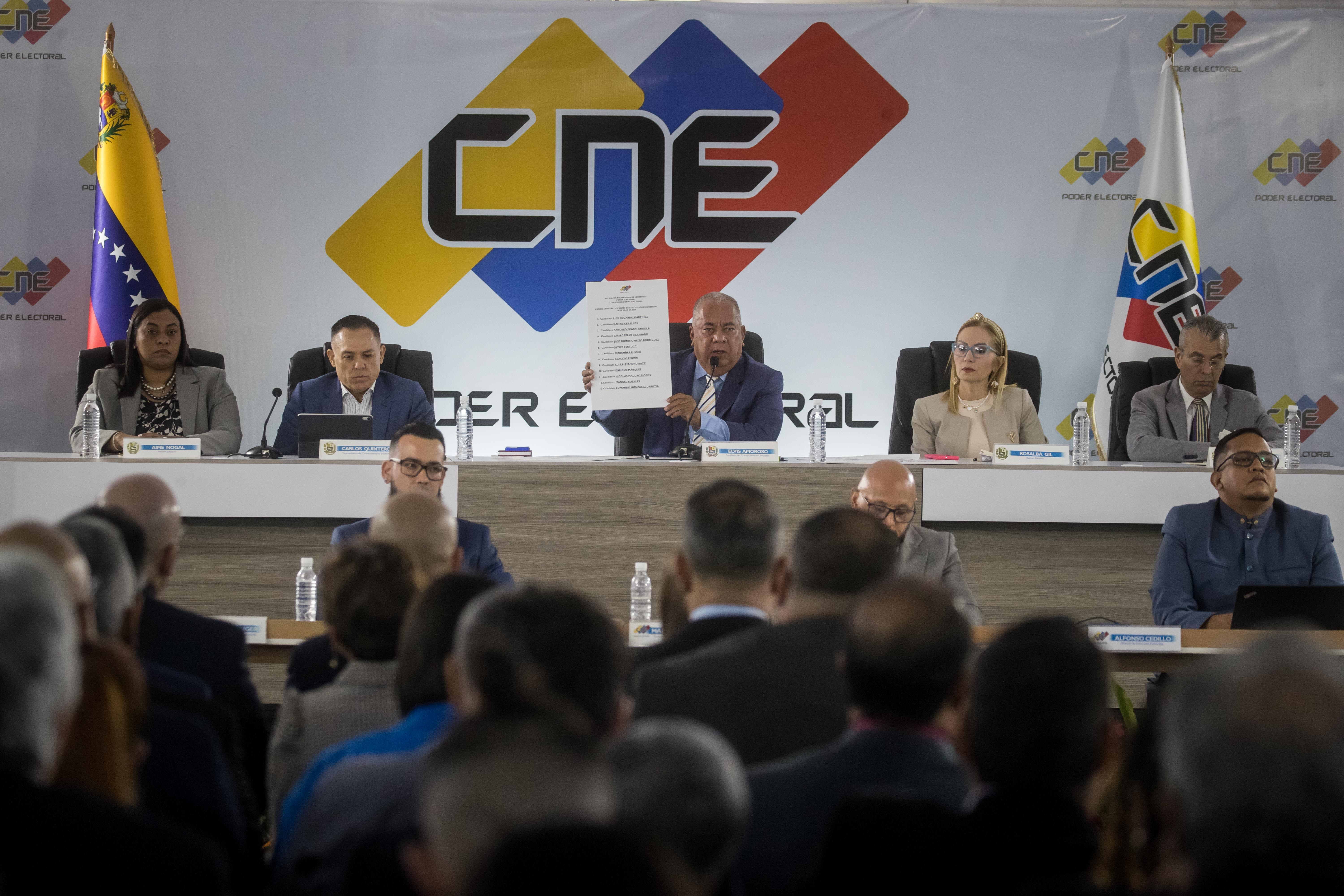 AME5695. CARACAS (VENEZUELA), 08/04/2024.- Elvis Amoroso (c), presidente del Consejo Nacional Electoral (CNE), muestra la lista oficial con los candidatos a elecciones presidenciales, este lunes en Caracas (Venezuela).El Consejo Nacional Electoral (CNE) de Venezuela comenzó este lunes el proceso para escoger las posiciones que ocuparán los 13 candidatos presidenciales en la boleta de votación que será usada en las elecciones del próximo 28 de julio. EFE/ MIGUEL GUTIERREZ