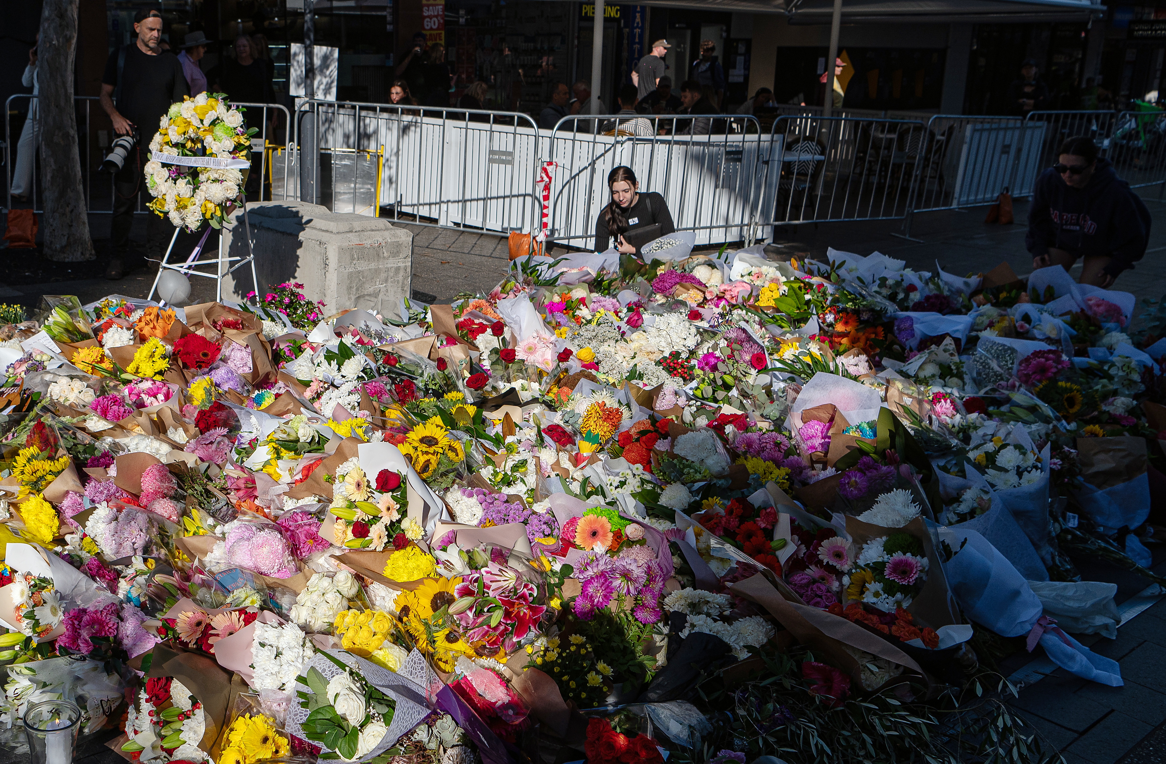 Sydney (Australia), 15/04/2024.- A woman places flowers at a makeshift memorial outside the Westfield Bondi Junction shopping centre in tribute to the victims of the Bondi Junction stabbing spree, in Sydney, Australia, 15 April 2024. Sydney is mourning six people who were stabbed to death at the Bondi Junction shopping centre. The man who fatally stabbed six people in the attack has been identified as 40-year-old Joel Cauchi, who moved to Sydney from Queensland last month. EFE/EPA/FLAVIO BRANCALEONE AUSTRALIA AND NEW ZEALAND OUT