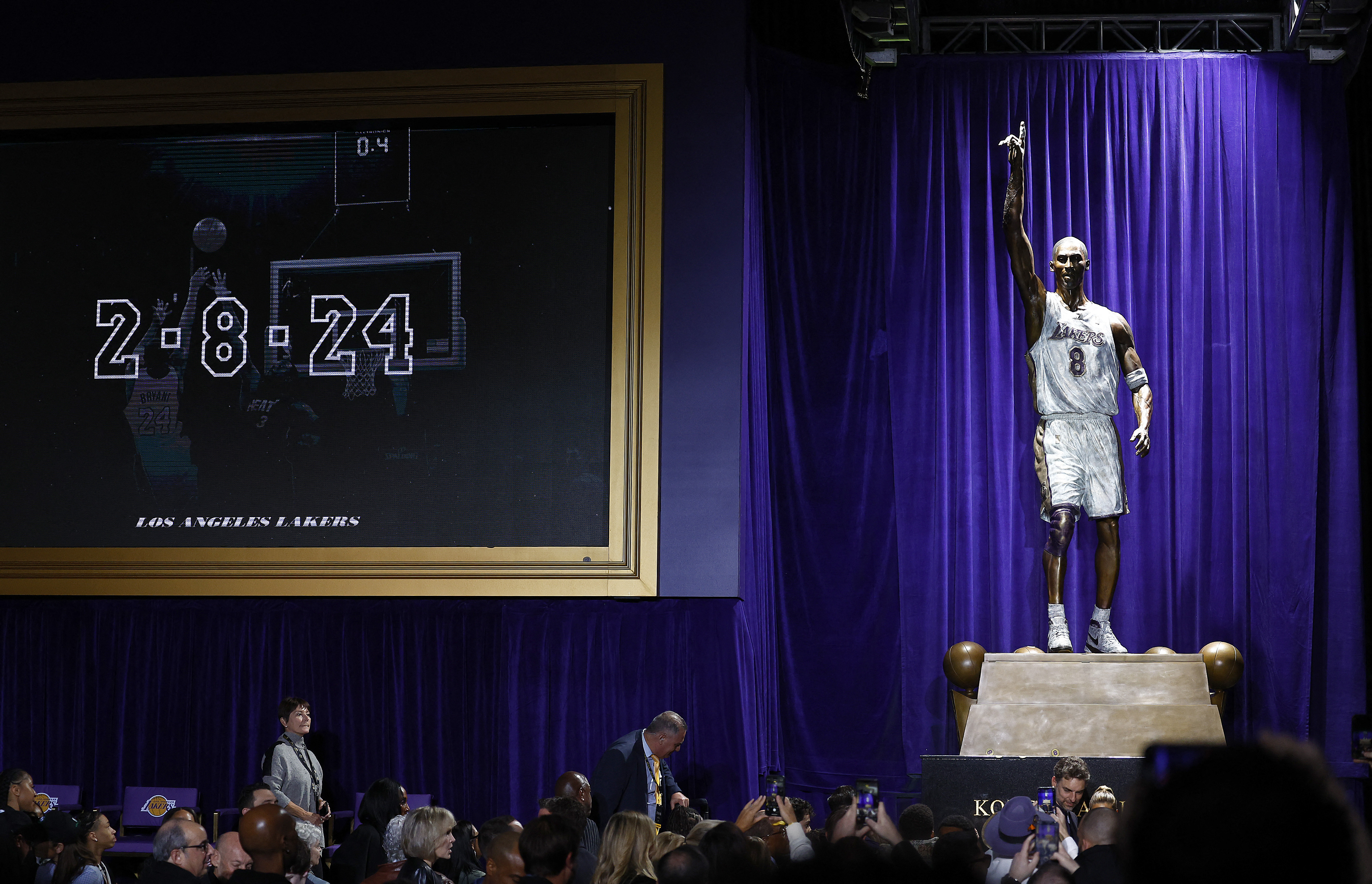 En la escultura, Kobe Bryant porta el uniforme de los Lakers con el número 8 y señala al cielo con el dedo índice derecho.
