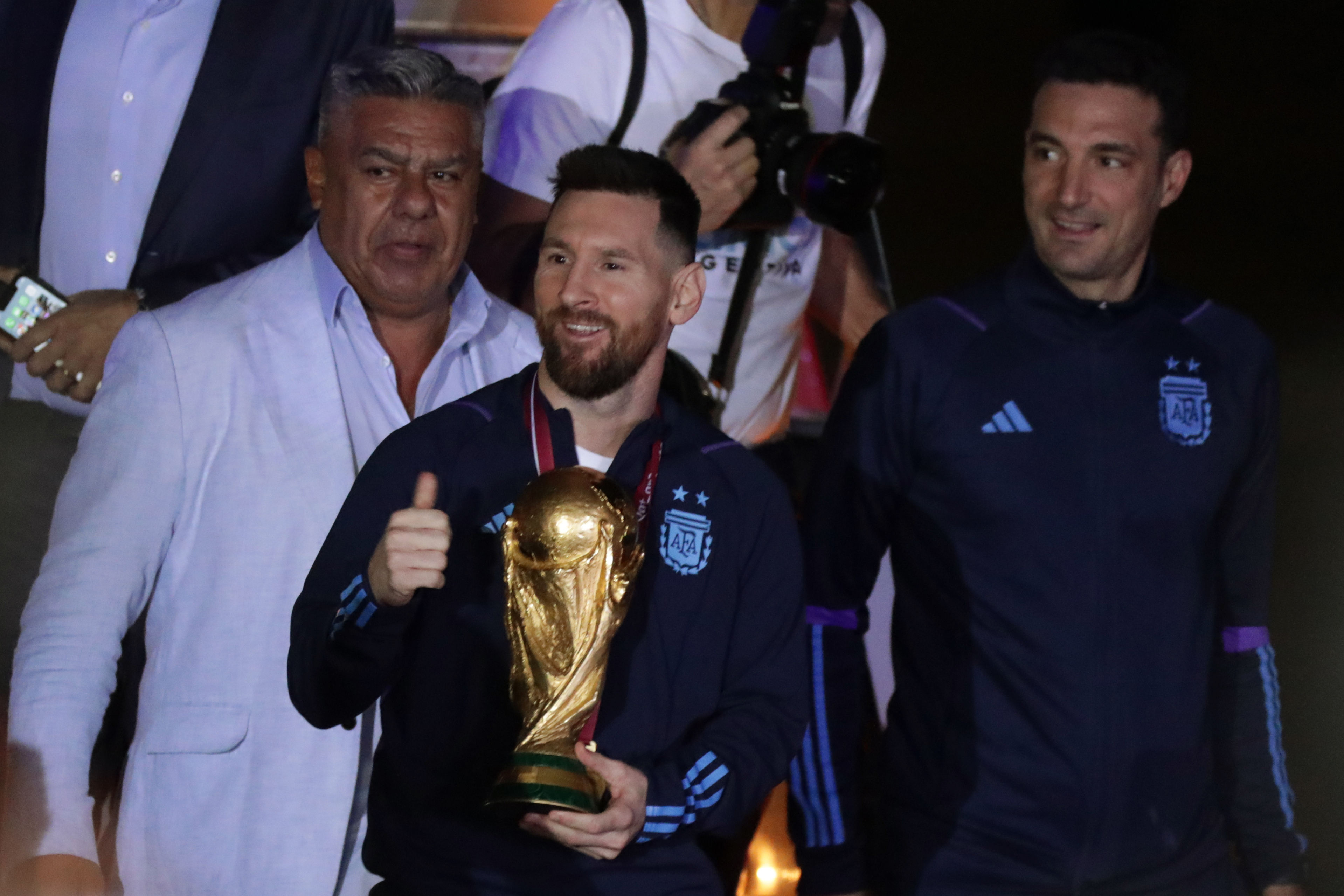 AMDEP9828. EZEIZA (ARGENTINA), 19/12/2022.- Lionel Messi (c) de la selección argentina de fútbol saluda con el trofeo del Mundial de Fútbol Qatar 2022 junto al seleccionador Lionel Scaloni (d) a su llegada hoy, al Aeropuerto Internacional de Ezeiza a unos 22km de Buenos Aires (Argentina). La selección argentina de fútbol, que este domingo se proclamó campeona del mundo en Catar tras vencer en la final a Francia en la tanda de penaltis, ya se encuentra en casa, donde fue recibida por una multitud de aficionados. EFE/ Raúl Martínez