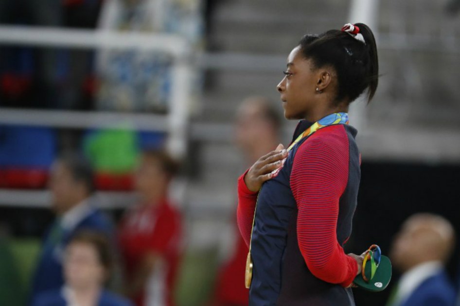 Simone Biles, de 19 años, escuchando el himno de Estados Unidos con su tercera medalla de oro en Río 2016. / AFP